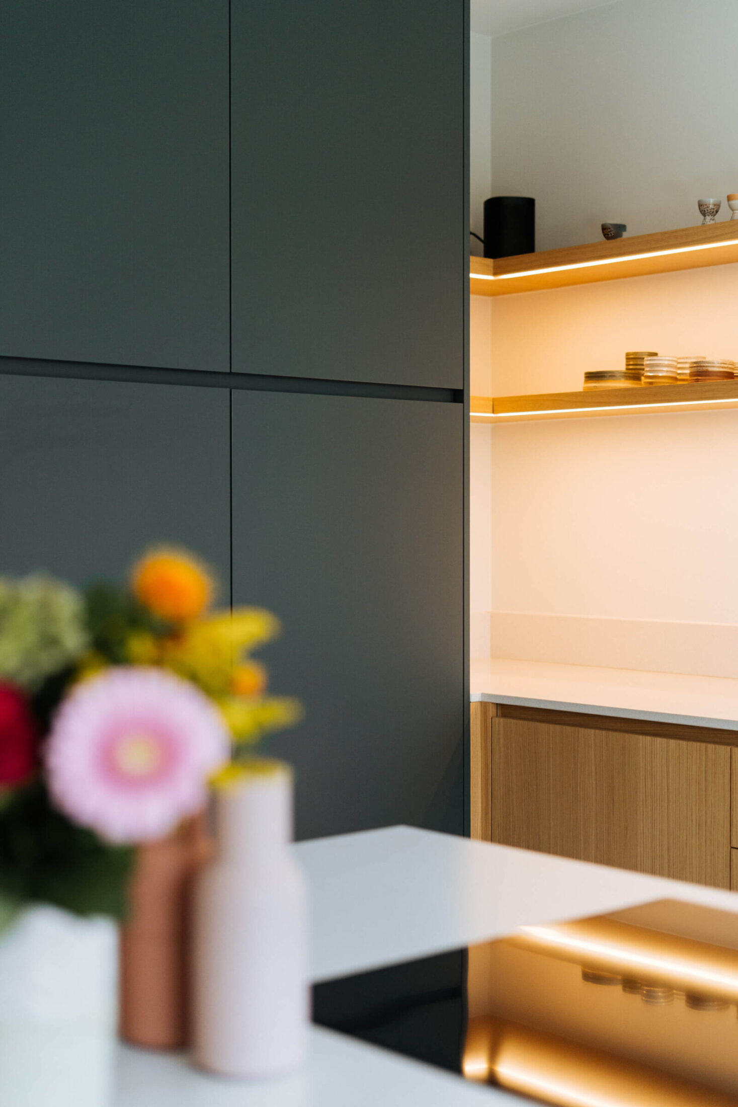 Detail van een landelijke keuken met donkergrijze kasten en verlichte eiken wandrekken in Aalter, Kaster Keukens