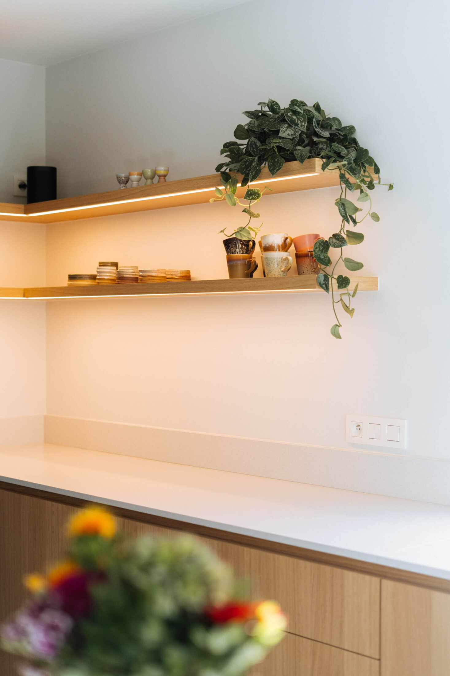 Detail van een landelijke keuken met eiken wandrekken met ledverlichting en wit werkblad in Aalter, Kaster Keukens