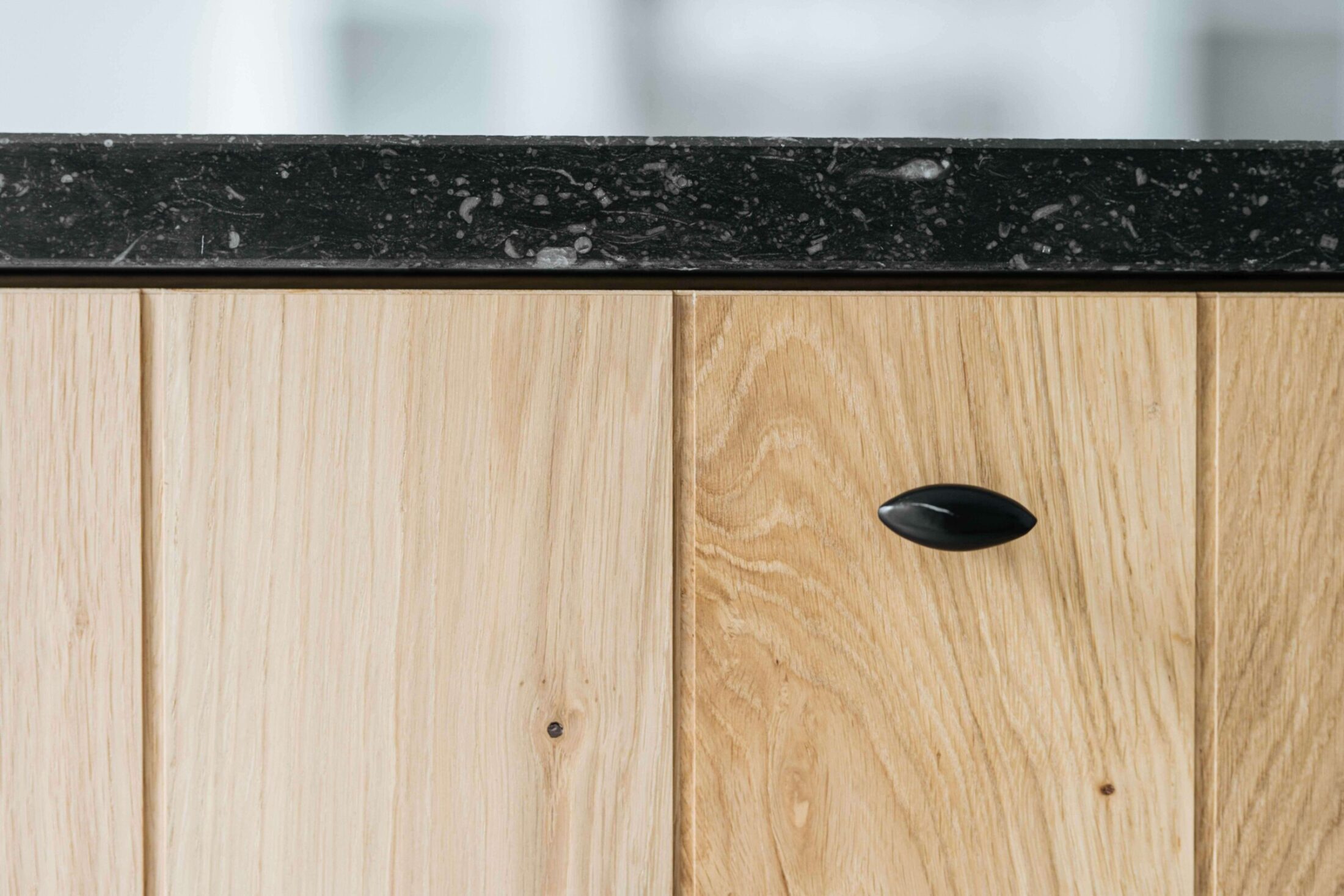 Detail van een landelijke keuken met eiken fronten, zwarte greep en donker natuursteen in Dadizele, Kaster Keukens