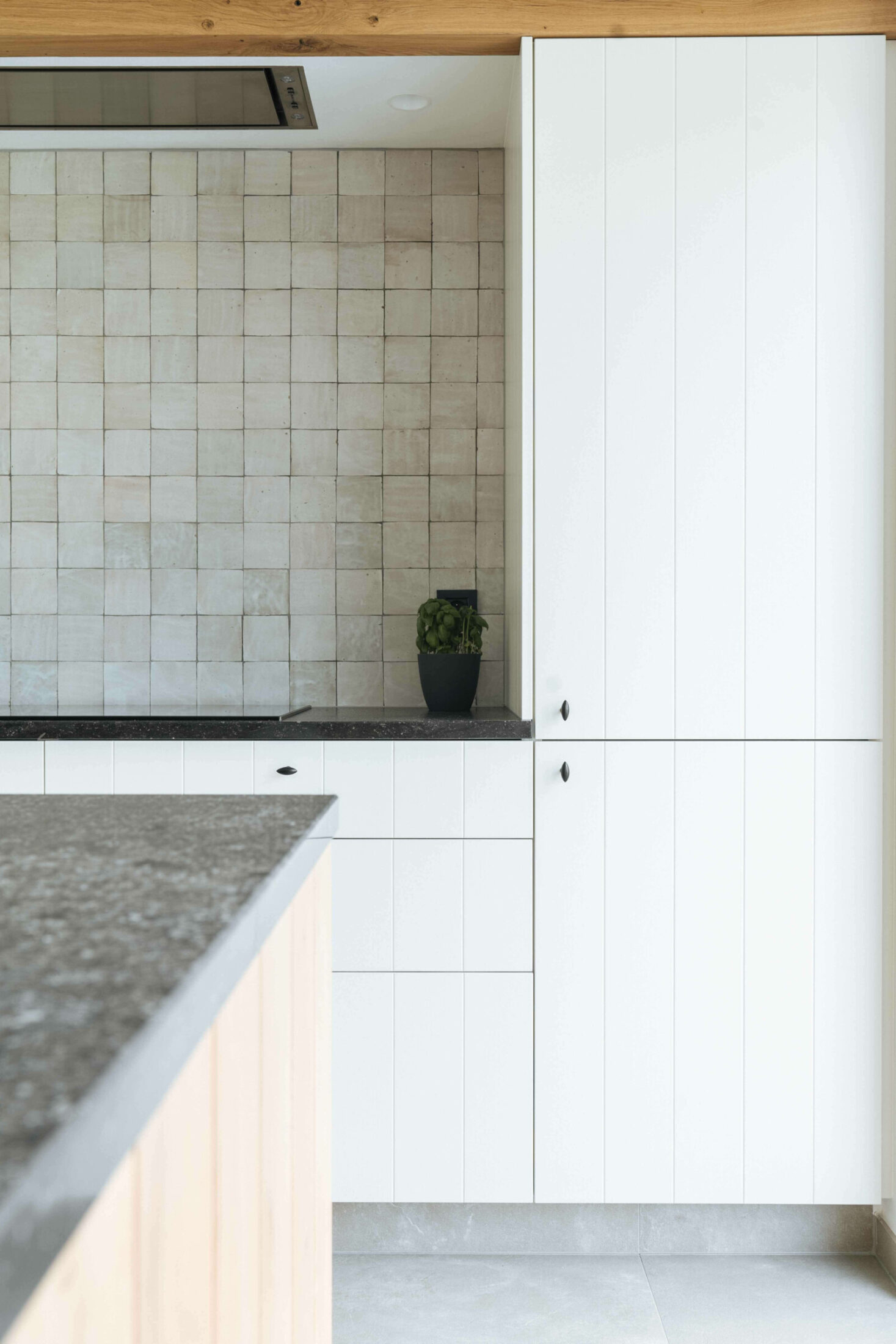 Detail van een landelijke keuken met witte kasten, donker werkblad en lichte wandtegels in Dadizele, Kaster Keukens