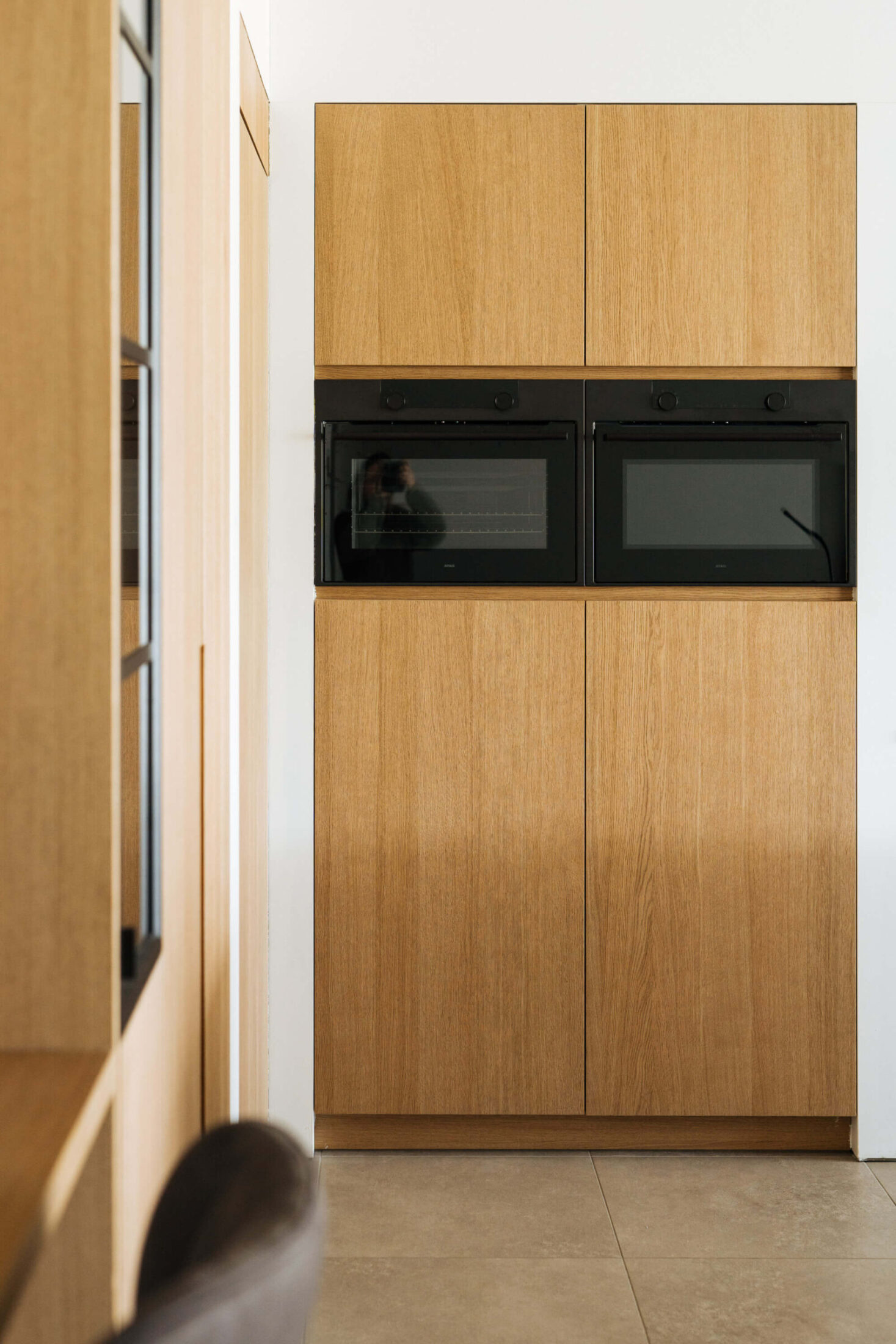 Landelijke keuken met eiken kolomkasten en zwarte ingebouwde ovens in De Haan, Kaster Keukens