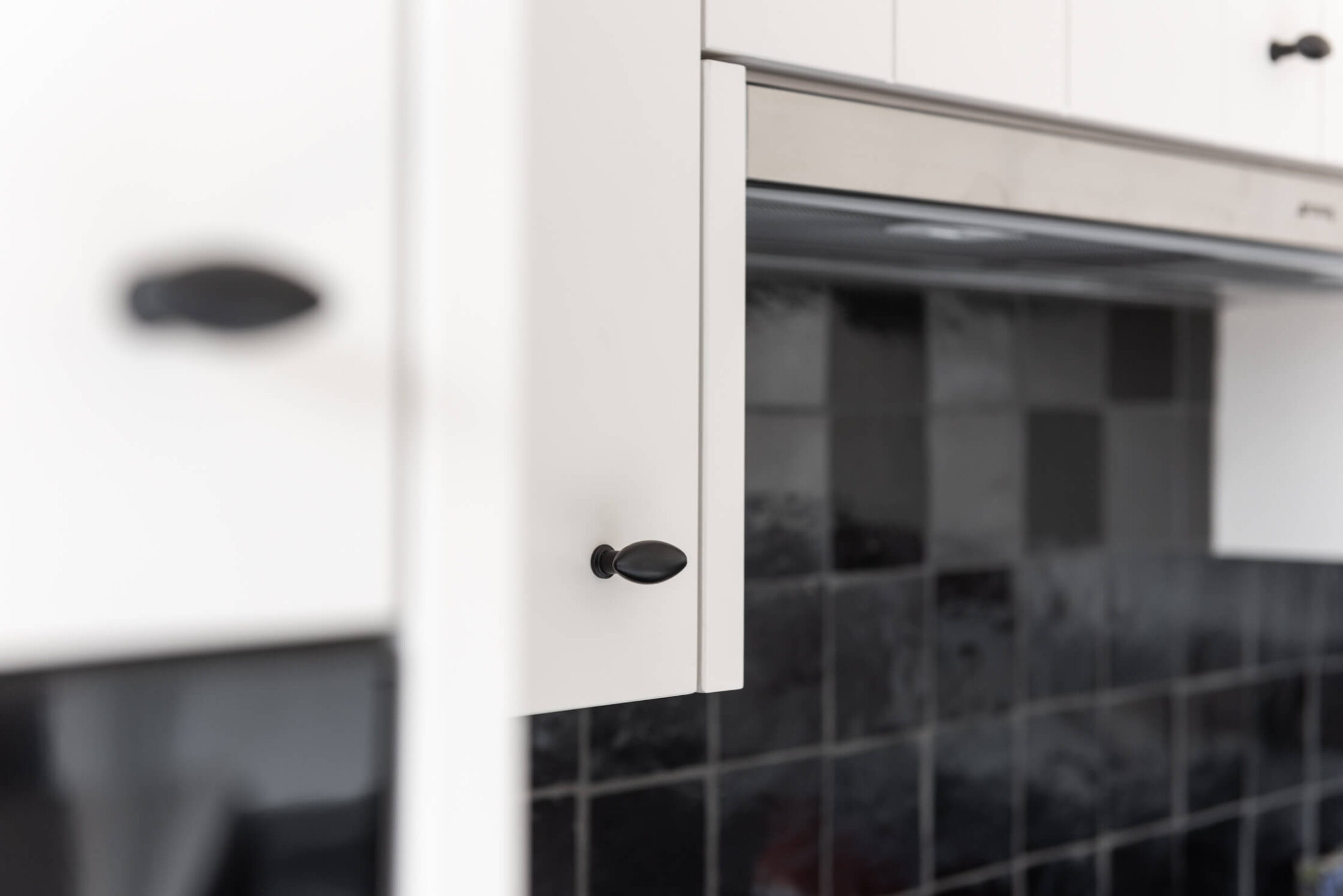 Detail van een landelijke keuken met zwarte knopgreep op witte fronten in Roeselare, Kaster Keukens
