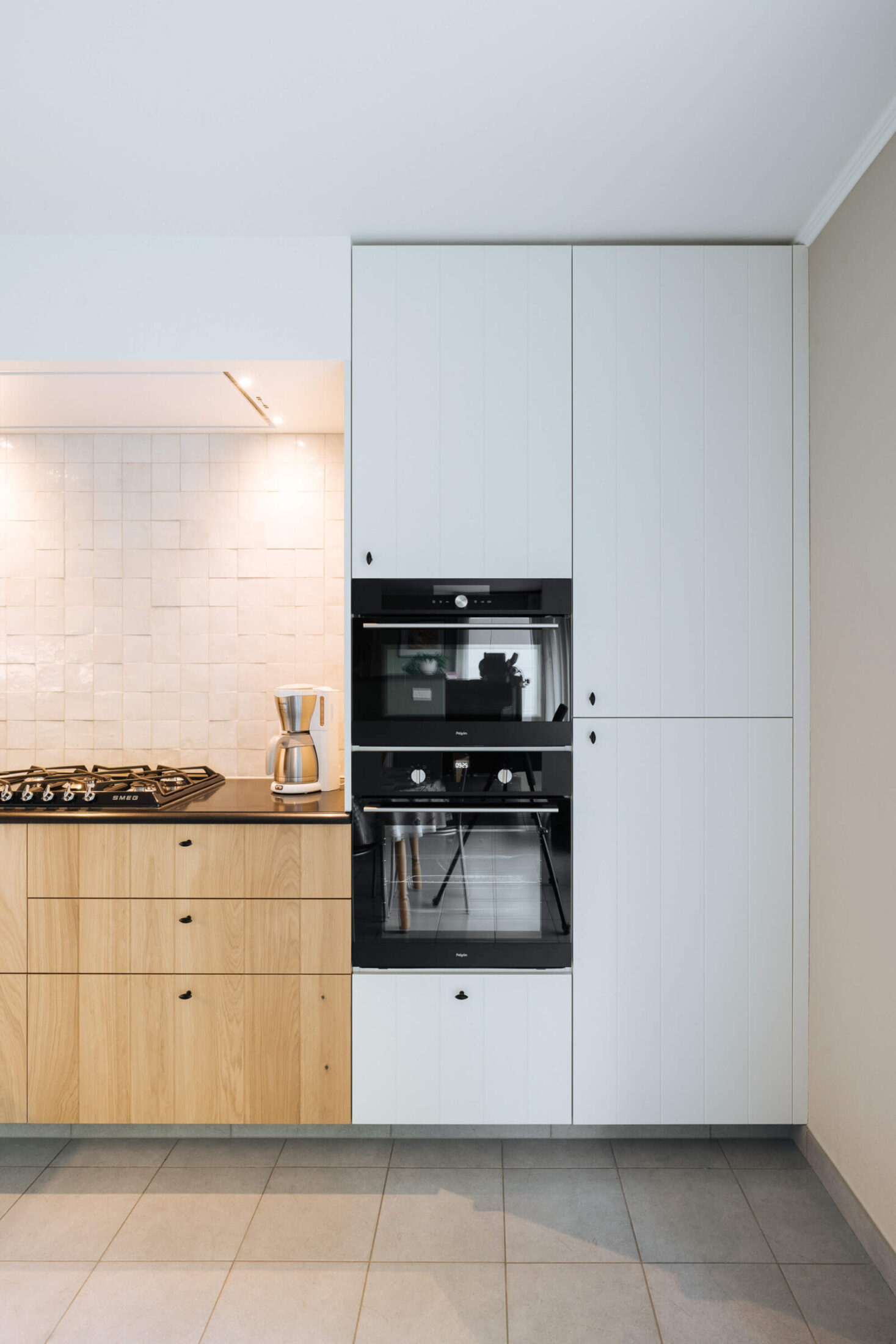 Landelijke keuken met witte hoge kasten, ingebouwde ovens en eiken laden in Veurne, Kaster Keukens
