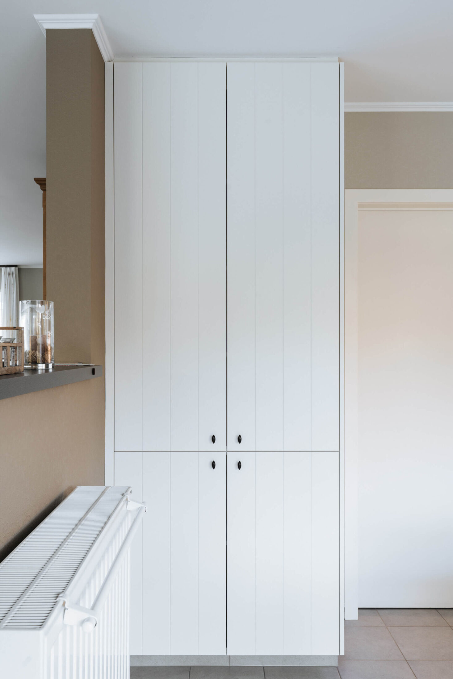 Detail van een landelijke keuken met witte hoge kast in Veurne, Kaster Keukens