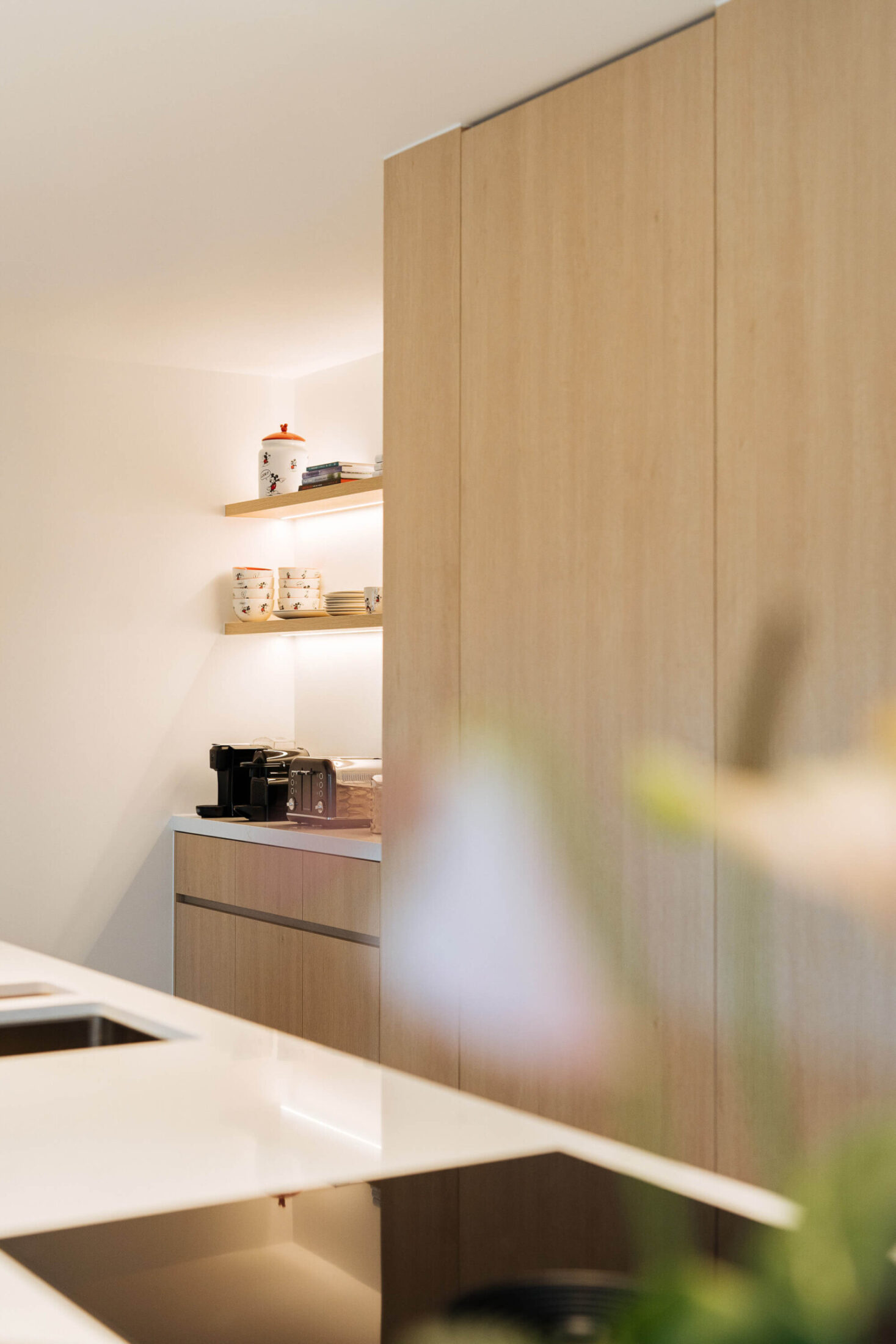 Detail van een moderne keuken met eiken kastenwand en verlichte nis in Bellegem, Kaster Keukens