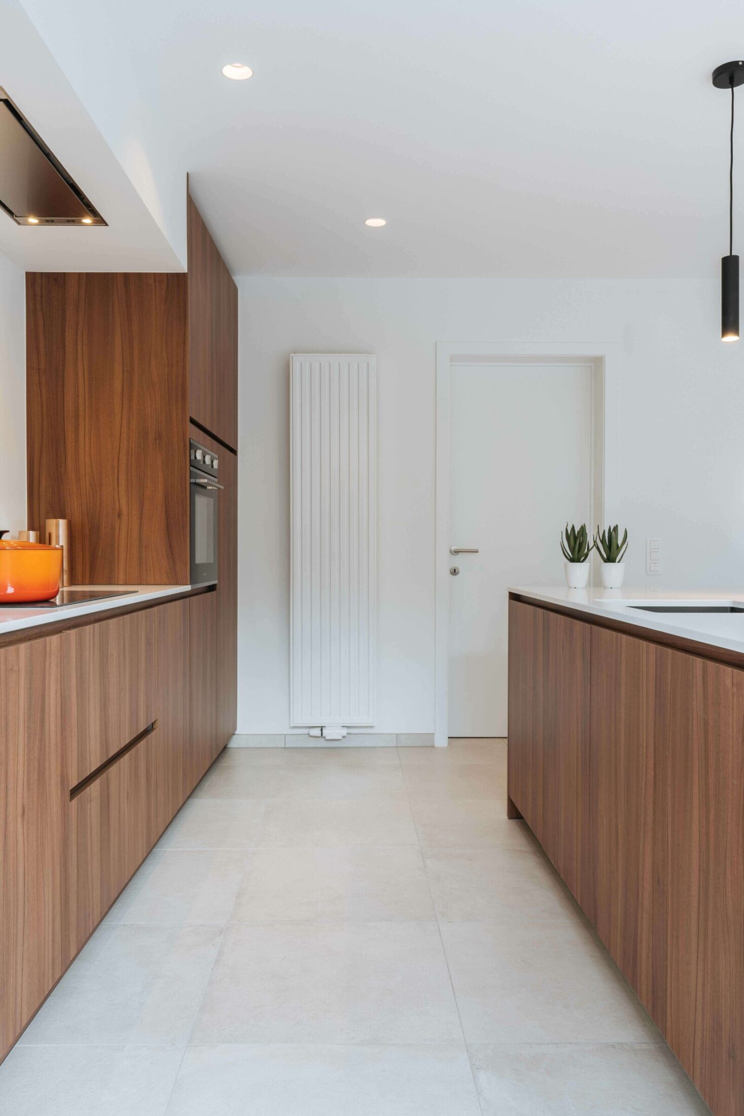 Moderne keuken met notelaar kastenwand en eiland op een lichte vloer in Kortrijk, Kaster Keukens