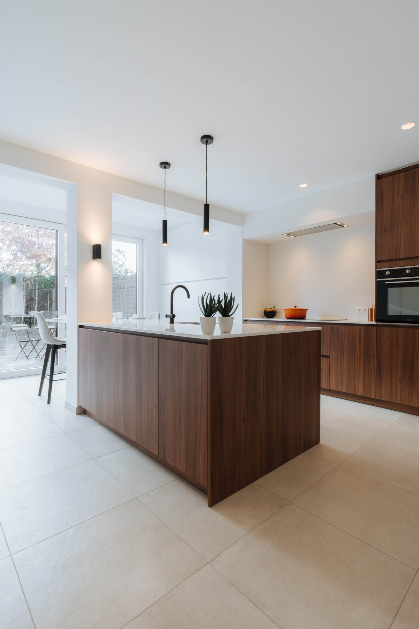 Moderne keuken met notelaar kookeiland en zwarte hanglampen in Kortrijk, Kaster Keukens