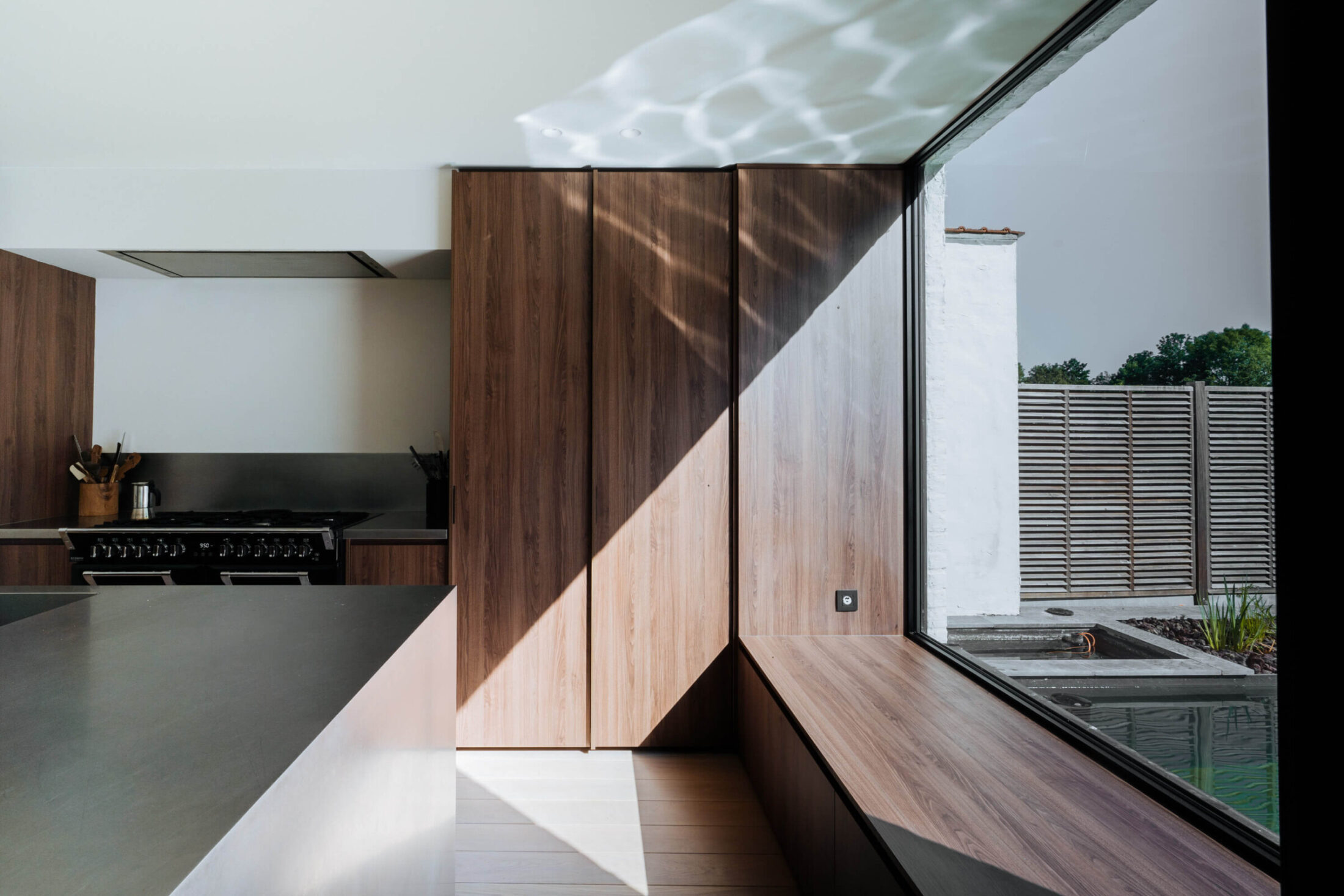Moderne keuken met notelaar hoge kasten en houten zitbank aan het raam in Mollem, Kaster Keukens