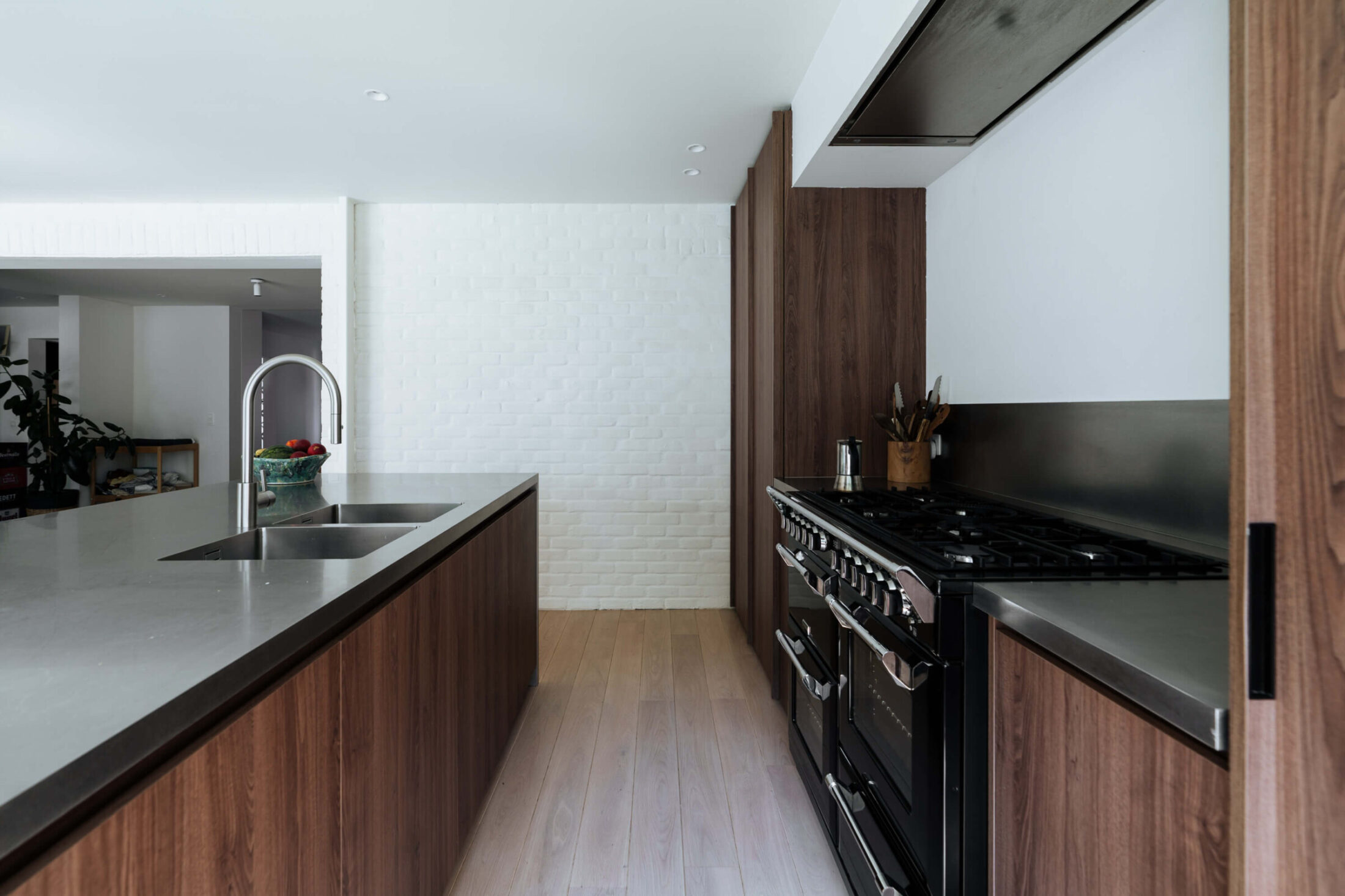 Moderne keuken met notelaar fronten, inox werkblad en zwart fornuis in Mollem, Kaster Keukens