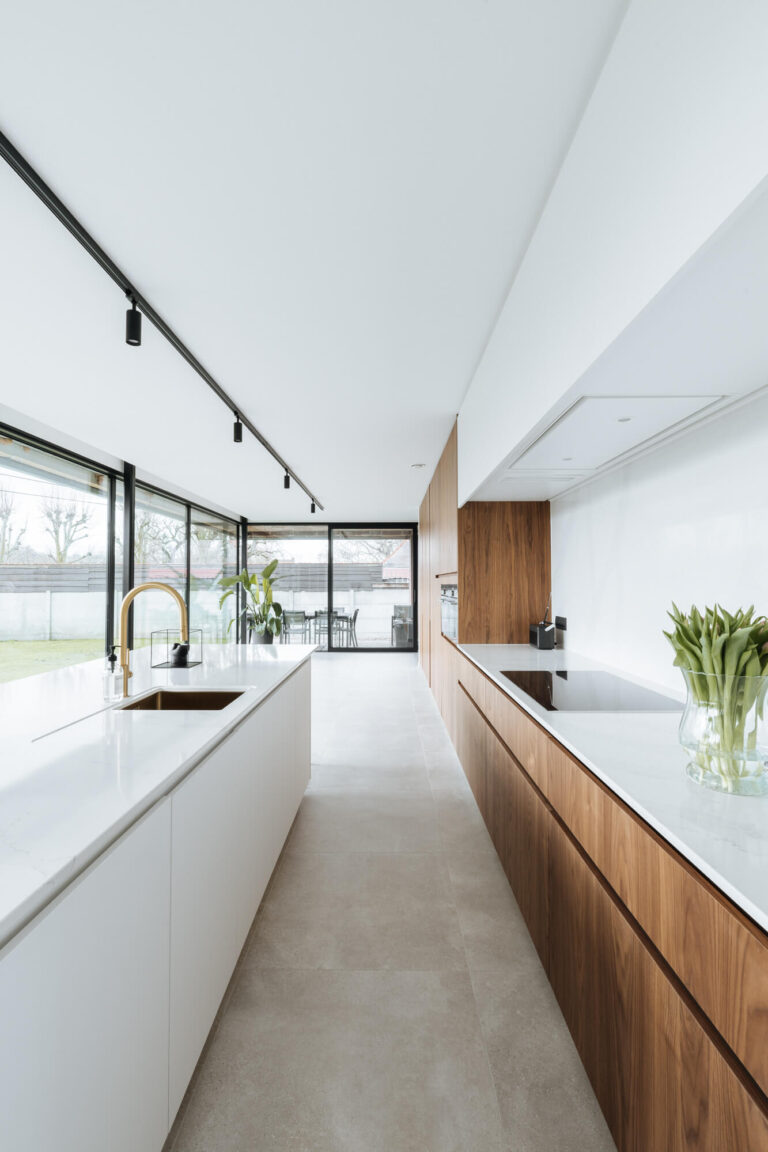 Moderne keuken met wit eiland en lange rij houten onderkasten in Roeselare, Kaster Keukens