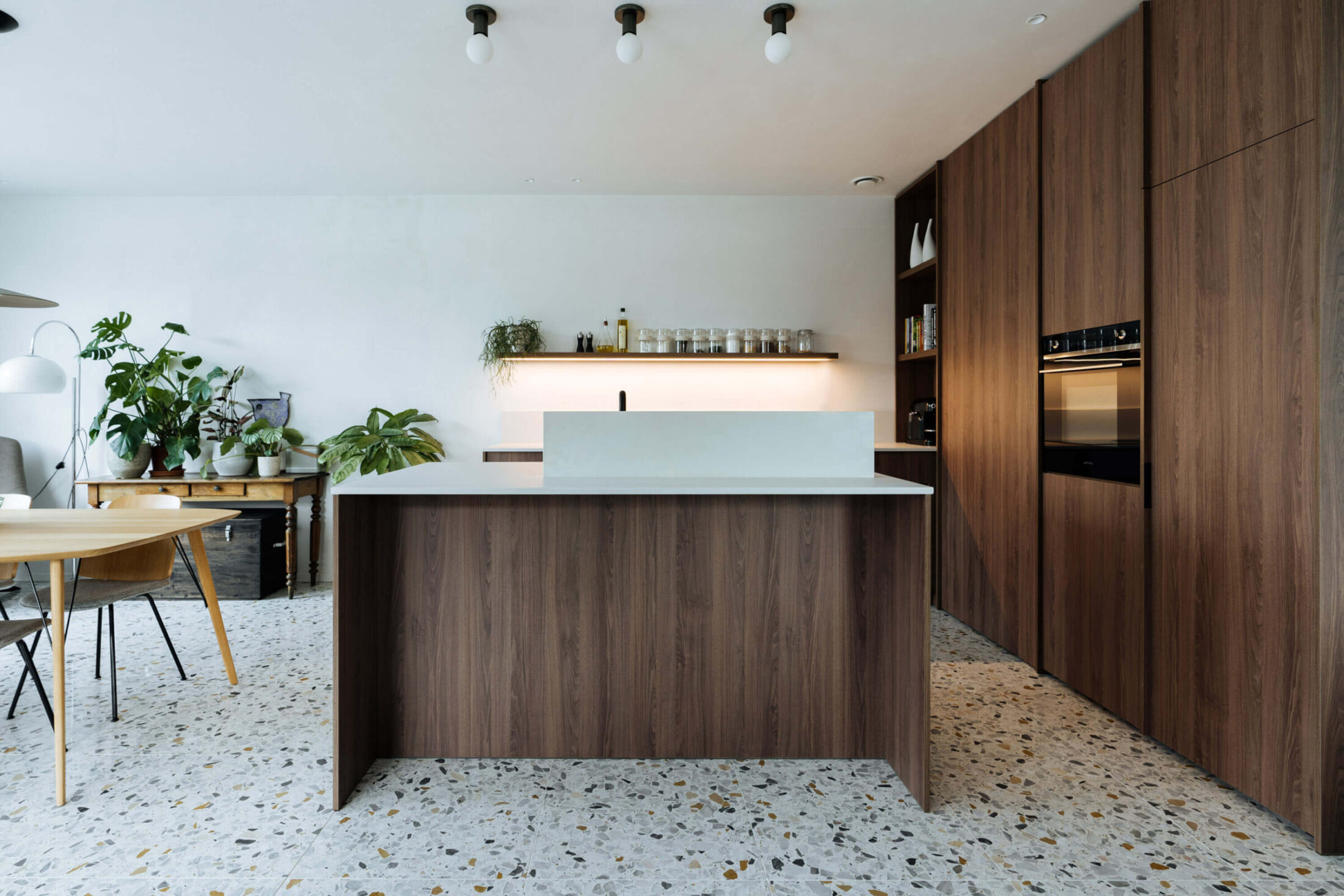 Moderne keuken met donker houten eiland en hoge kastenwand met oven in Roeselare, Kaster Keukens