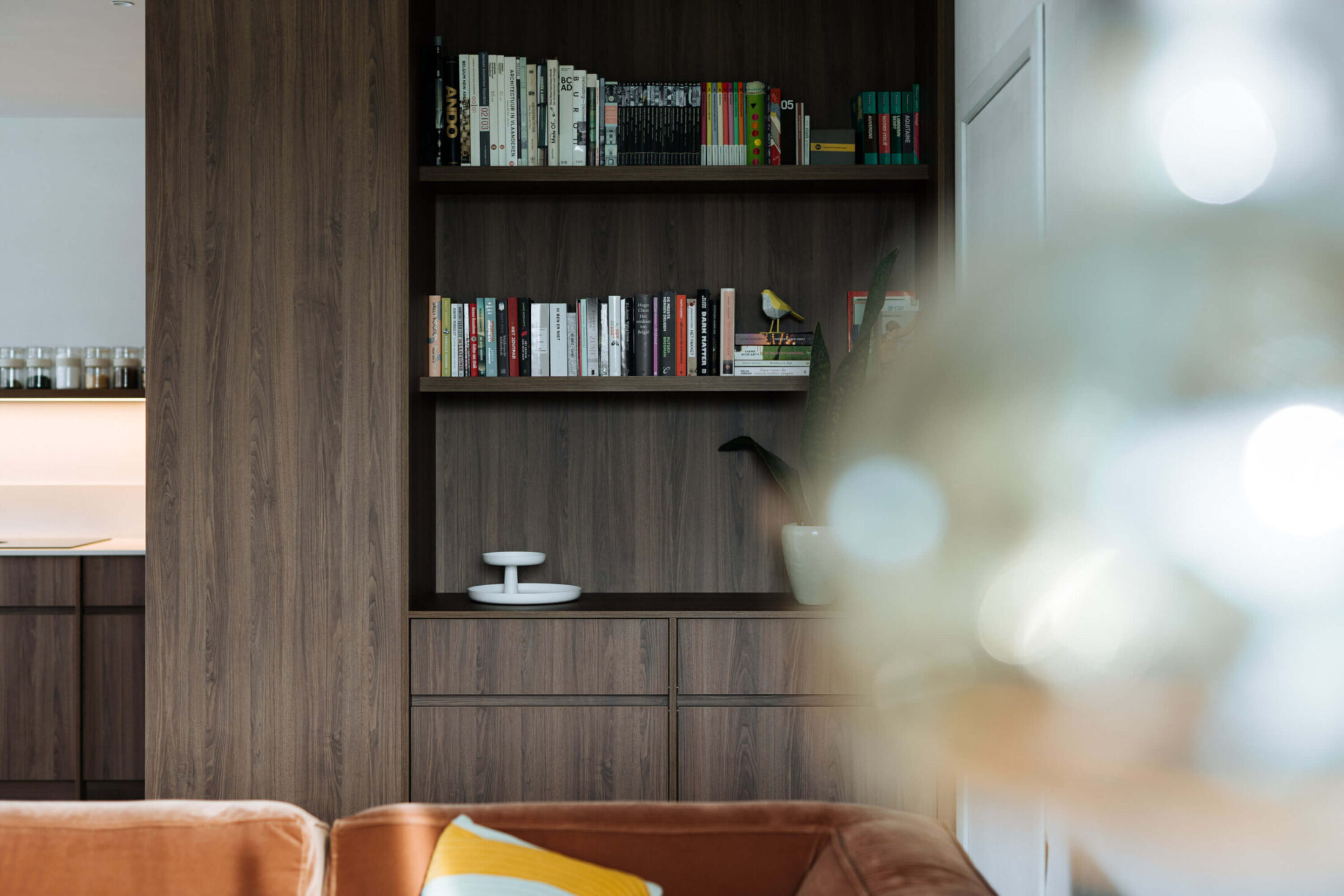 Moderne keuken met donkere houten boekenkast en open rekken naast de zithoek in Roeselare, Kaster Keukens