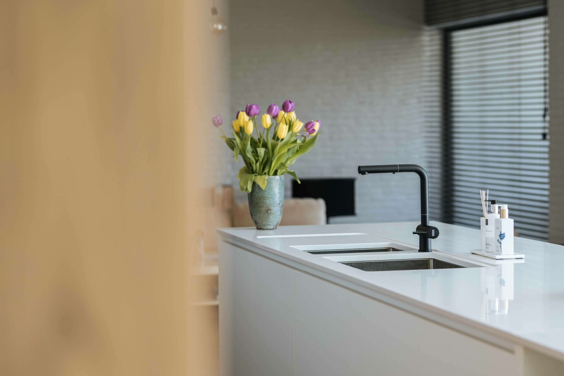 Detail van een moderne keuken met zwarte kraan en spoelbak in wit werkblad in Roeselare, Kaster Keukens