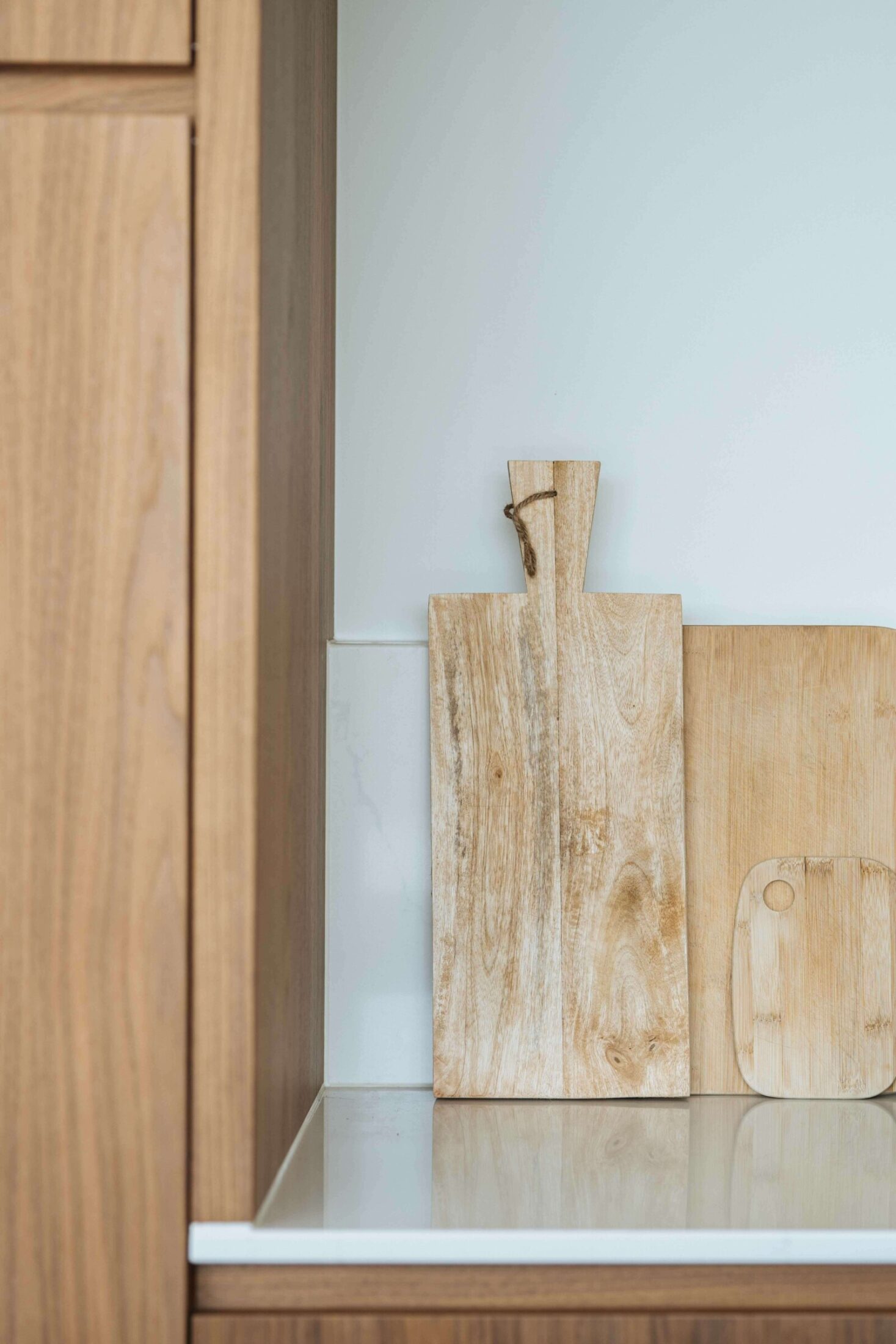 Detail van een moderne keuken met houten fronten en snijplanken op het werkblad in Roeselare, Kaster Keukens