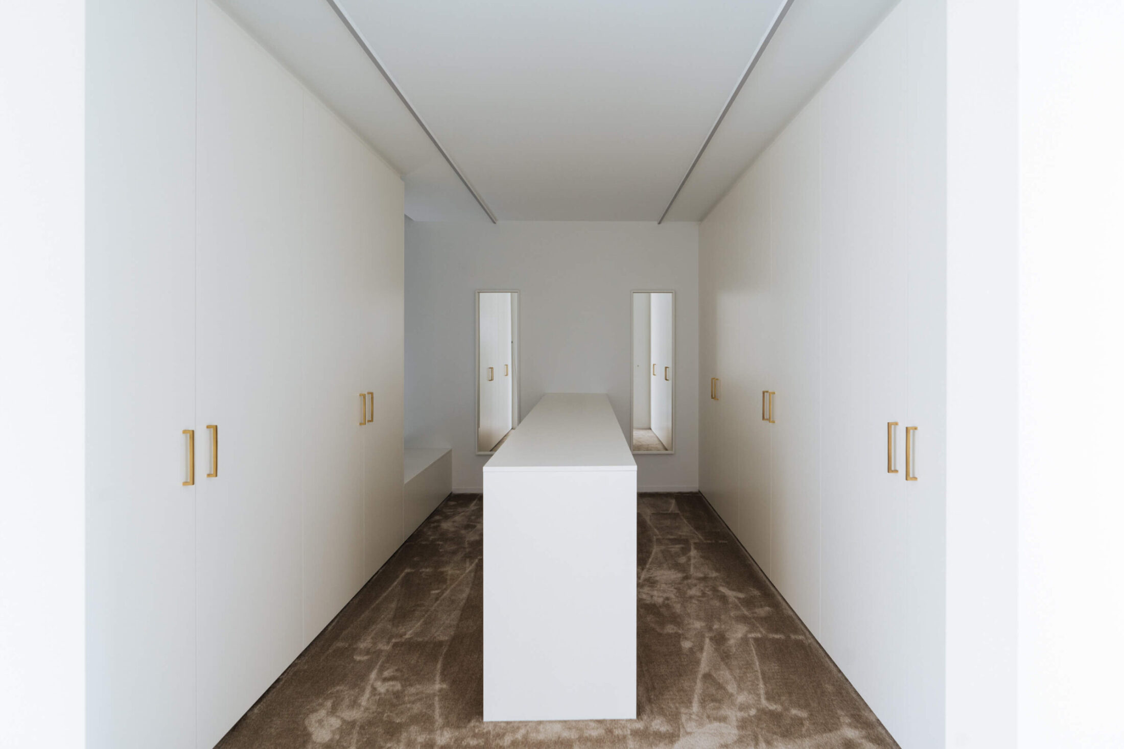 Moderne keuken met witte kastenwanden aan beide zijden en wit middenblok in Wevelgem, Kaster Keukens