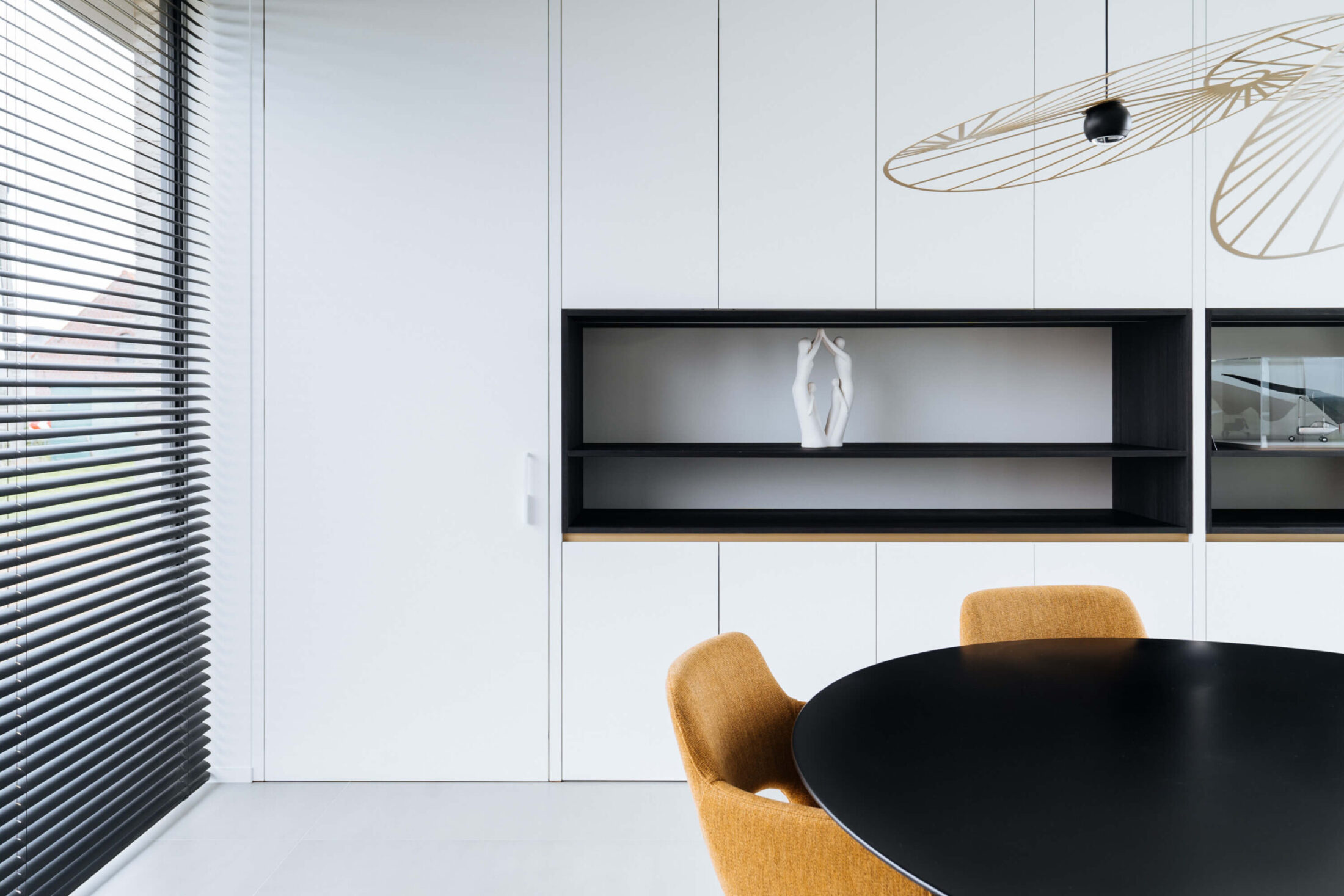 Moderne keuken met witte kastenwand, zwarte open nis en ronde eettafel in Wevelgem, Kaster Keukens