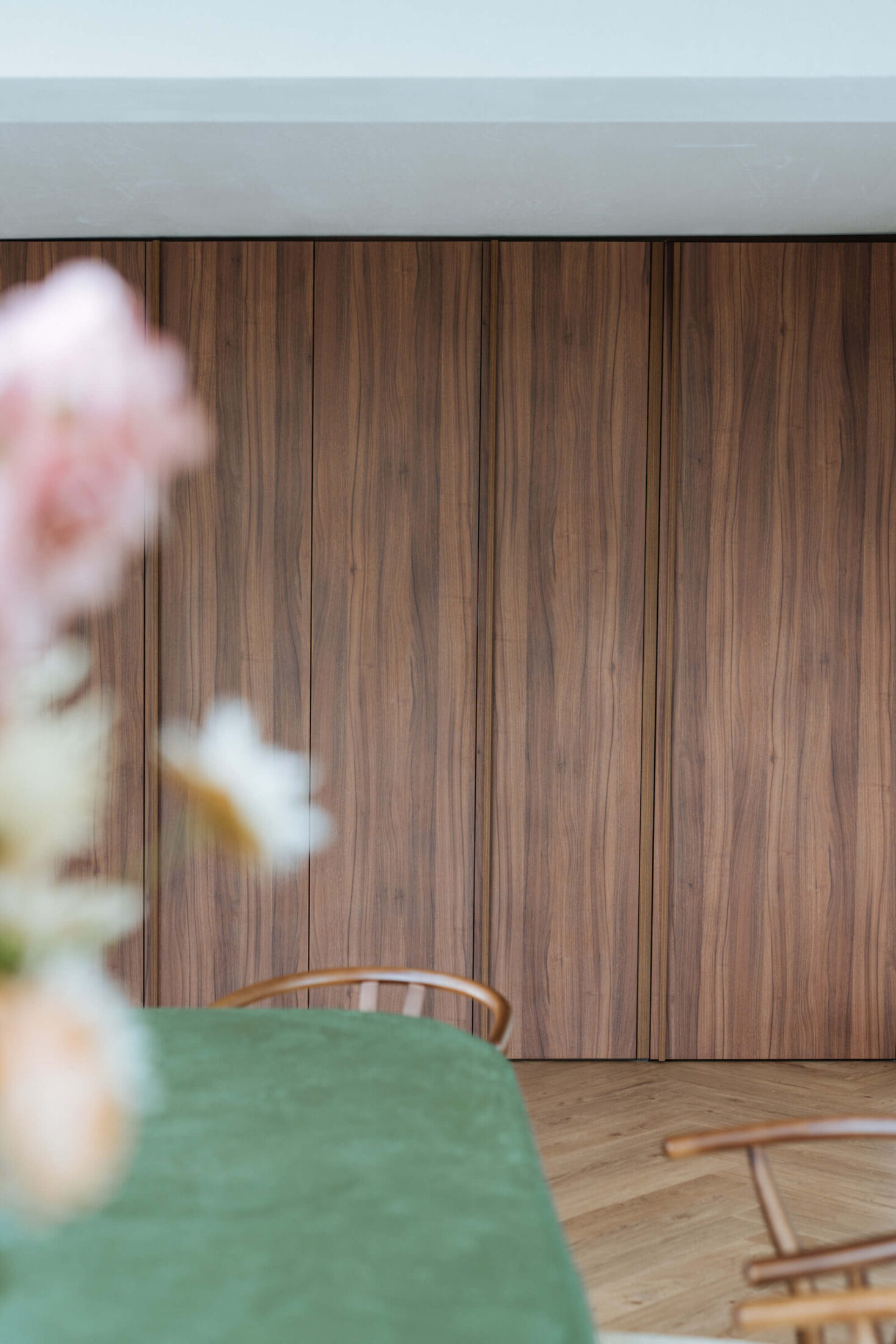 Detail van een scandinavische keuken met notelaar kastenwand achter de eettafel in Ardooie, Kaster Keukens