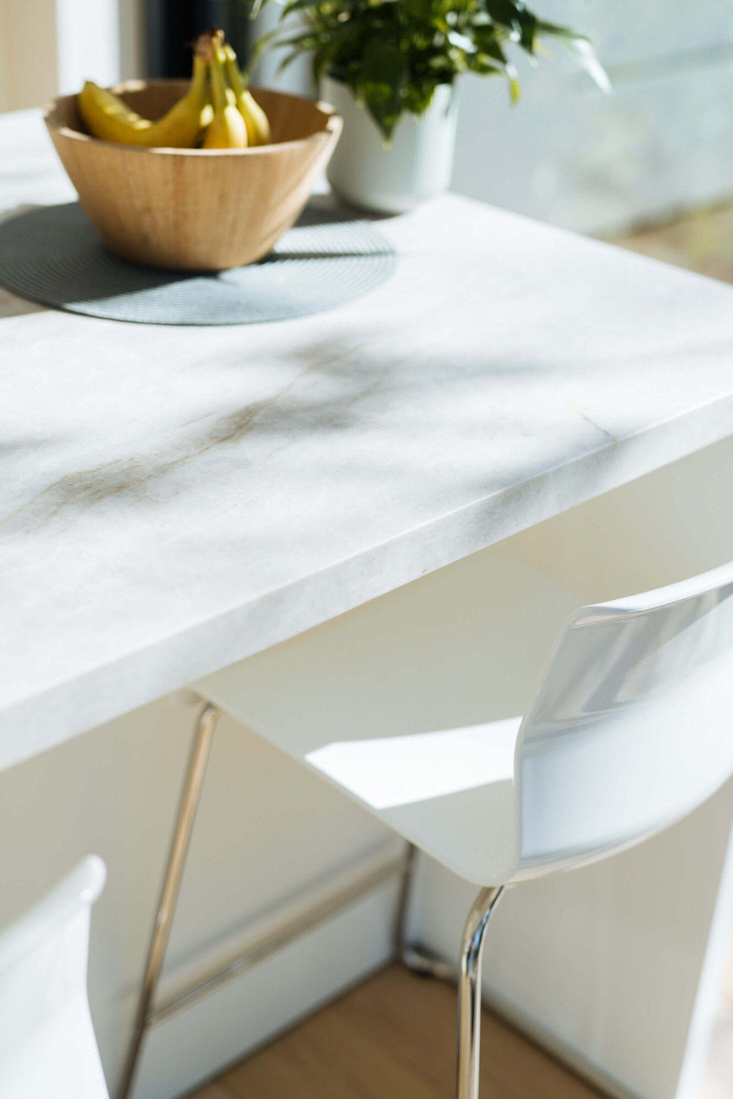Detail van een scandinavische keuken met natuurstenen werkblad en witte barkruk in Brugge, Kaster Keukens