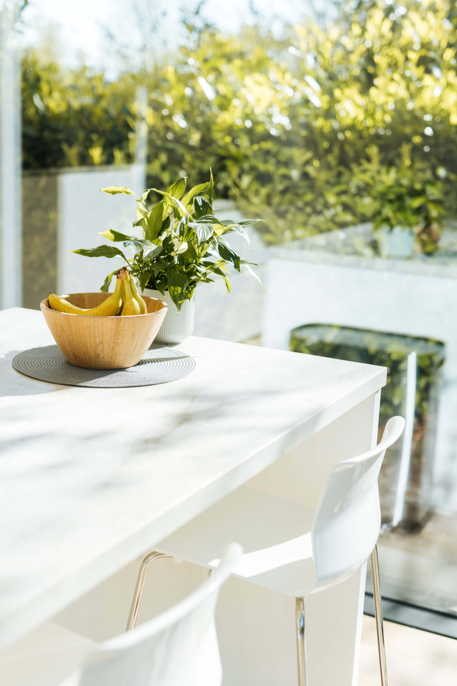 Detail van een scandinavische keuken met wit eiland en barkrukken bij het raam in Brugge, Kaster Keukens
