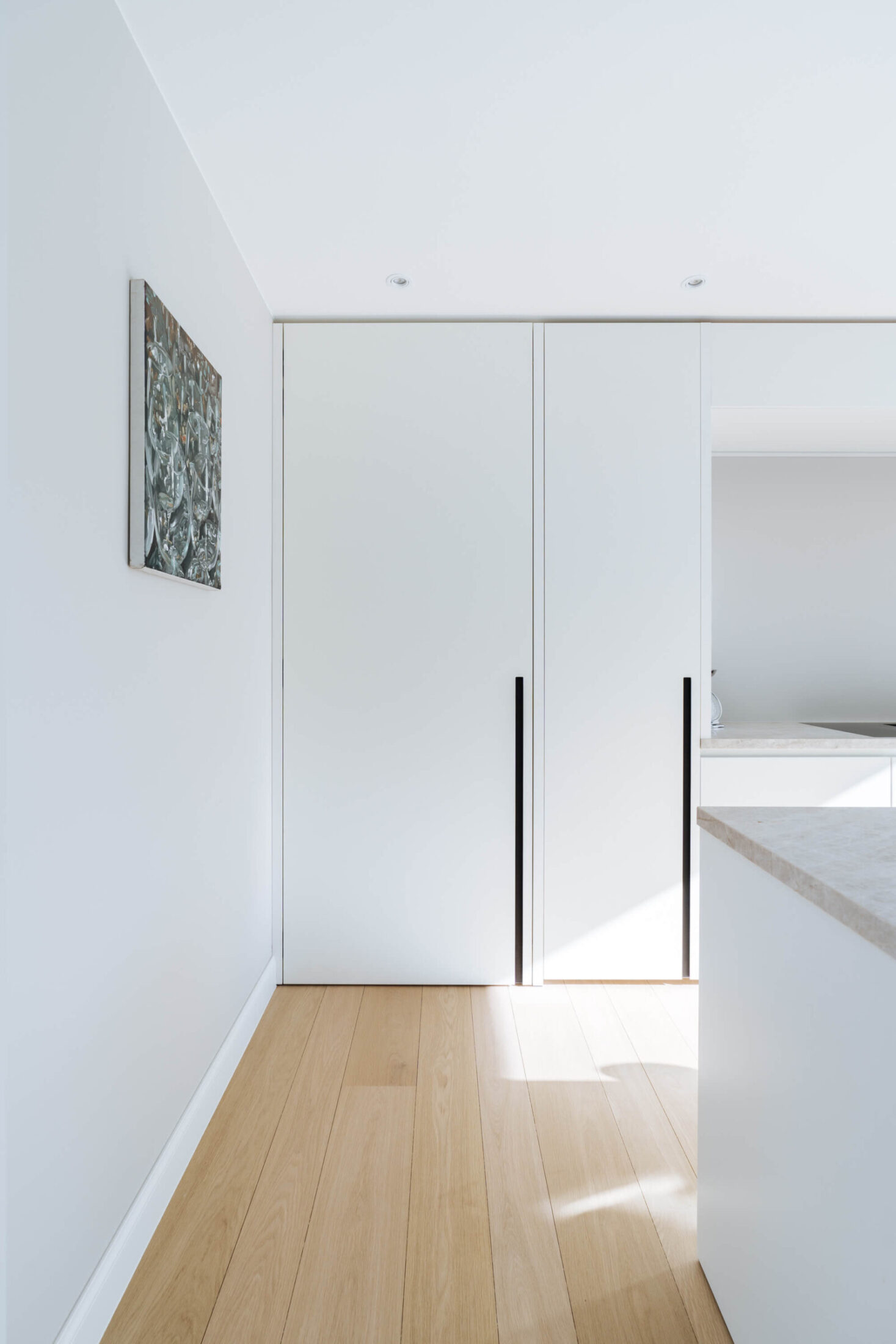 Detail van een scandinavische keuken met witte hoge kasten met zwarte grepen in Brugge, Kaster Keukens
