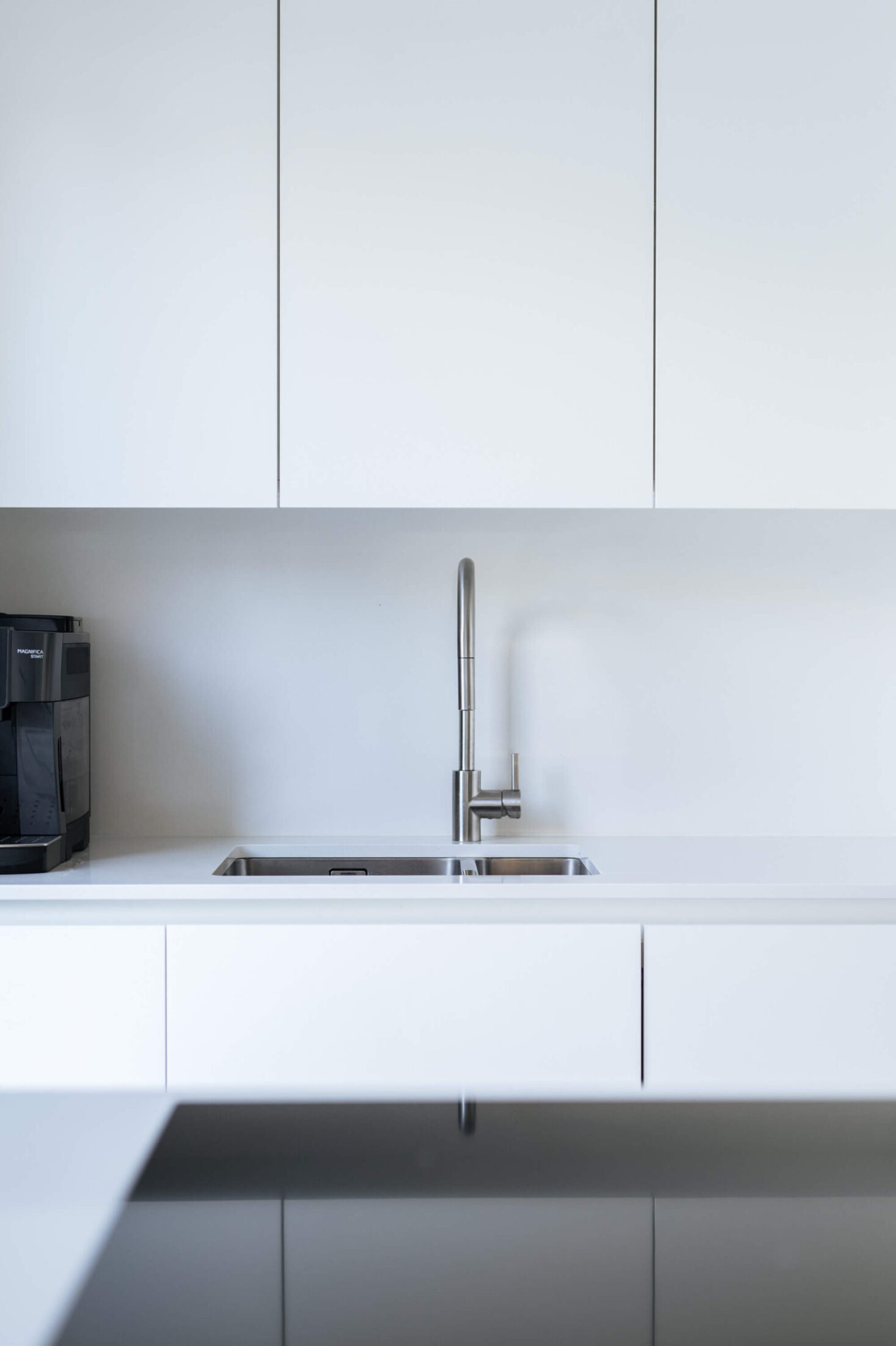 Detail van een Scandinavische keuken met inox kraan en witte bovenkasten in Brugge, Kaster Keukens