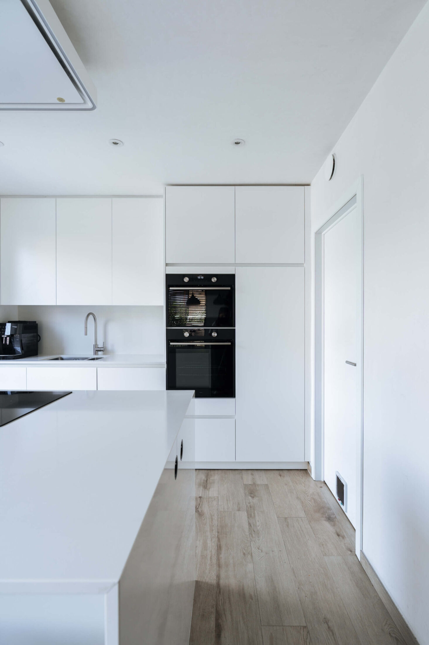 Scandinavische keuken met witte kasten en houten vloer in Brugge, Kaster Keukens