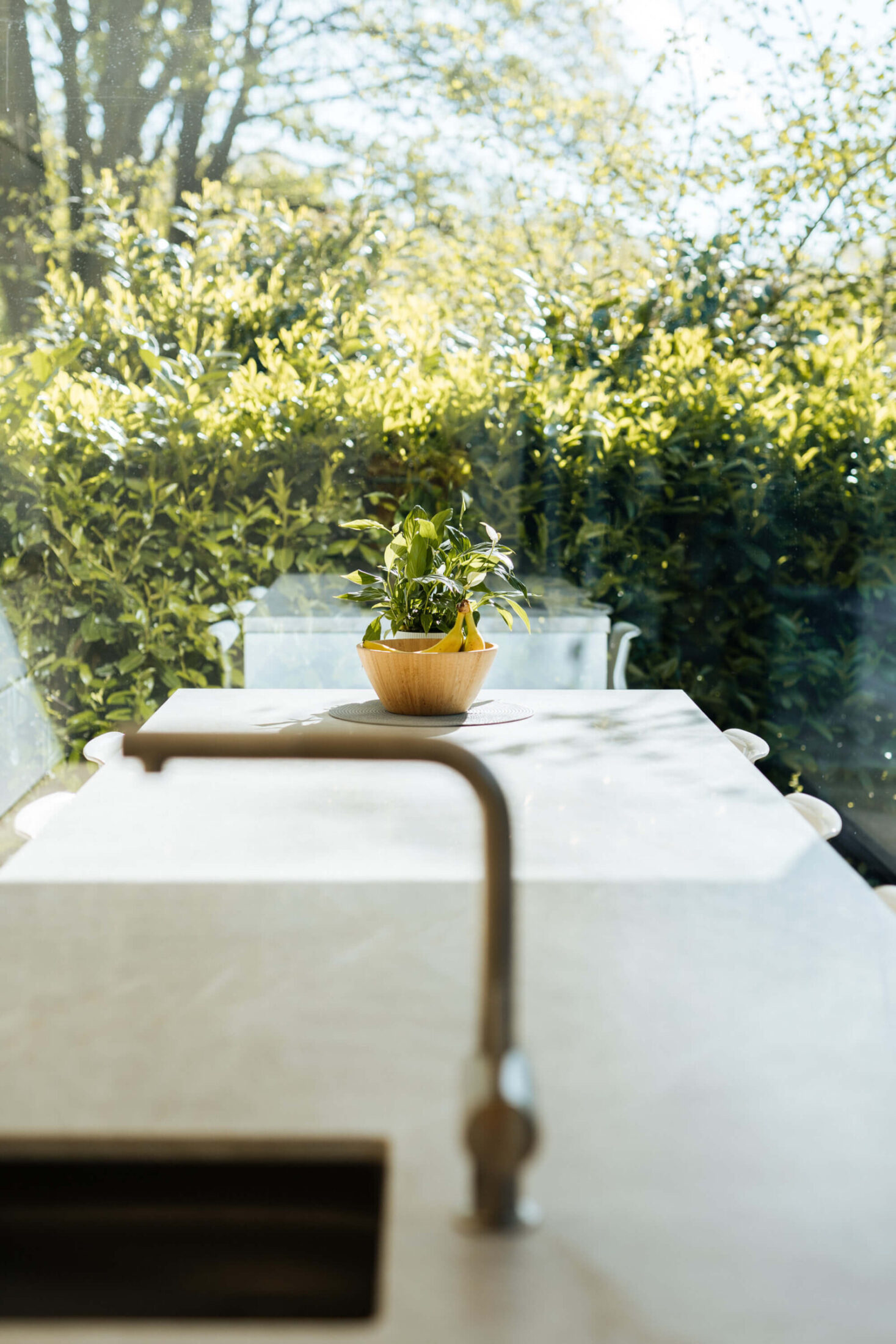 Detail van een scandinavische keuken met kraan en zicht op de tuin in Brugge, Kaster Keukens
