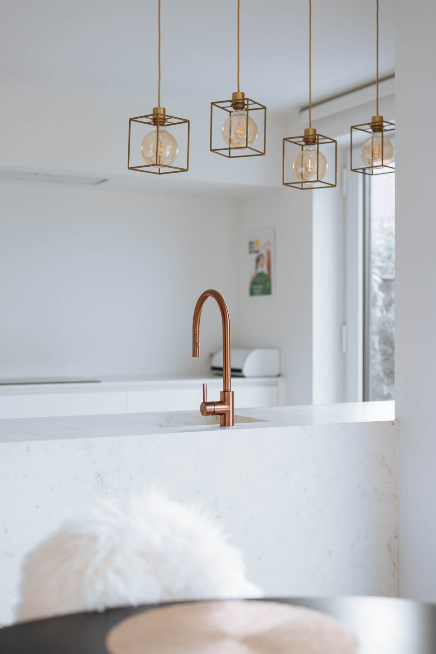 Detail van een Scandinavische keuken met koperen kraan en hanglampen boven het eiland in Herzele, Kaster Keukens