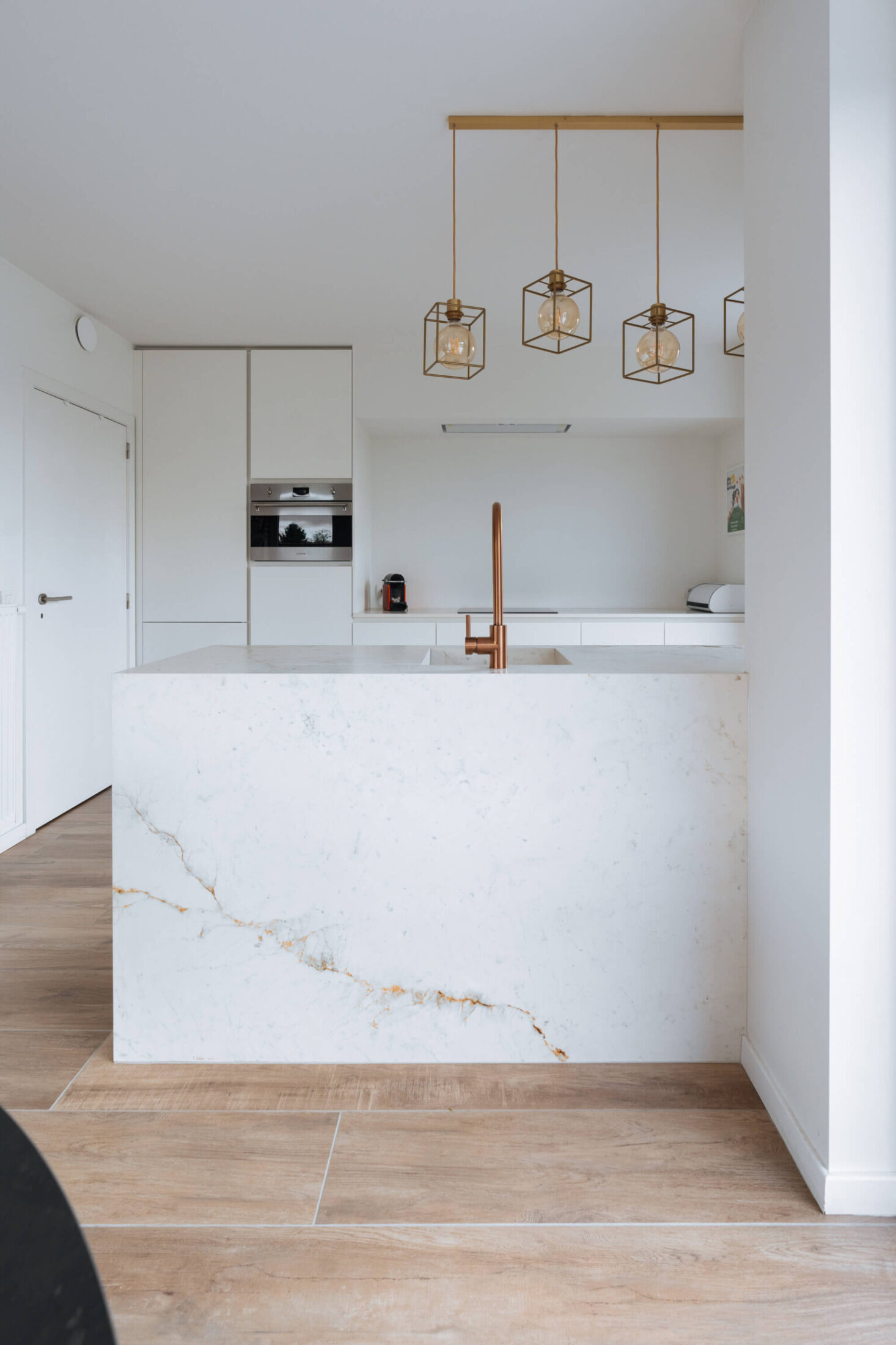 Scandinavische keuken met marmerlook eiland en witte kastenwand in Herzele, Kaster Keukens