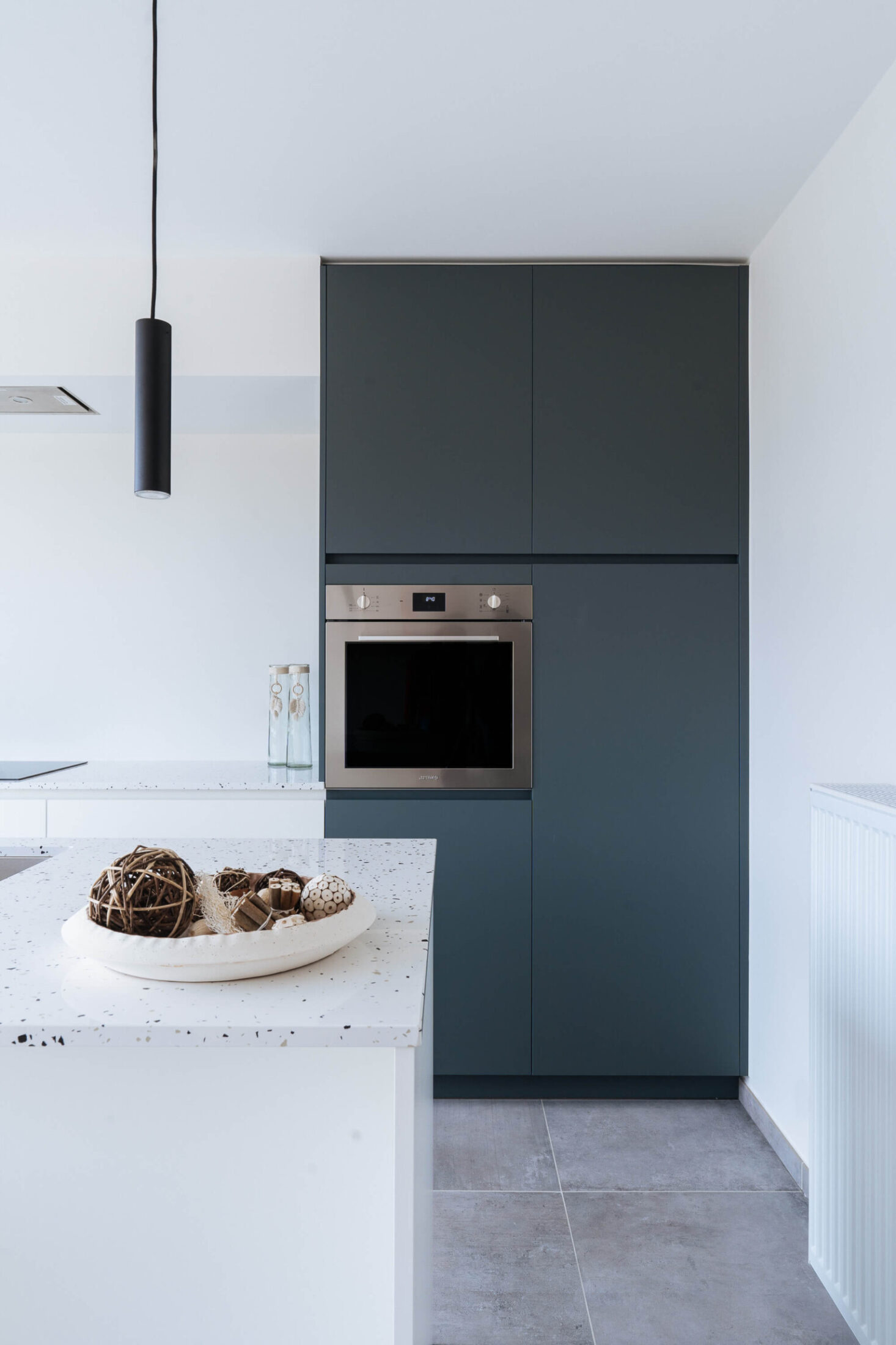 Scandinavische keuken met donkergroene hoge kast, oven en hanglamp in Kortrijk, Kaster Keukens
