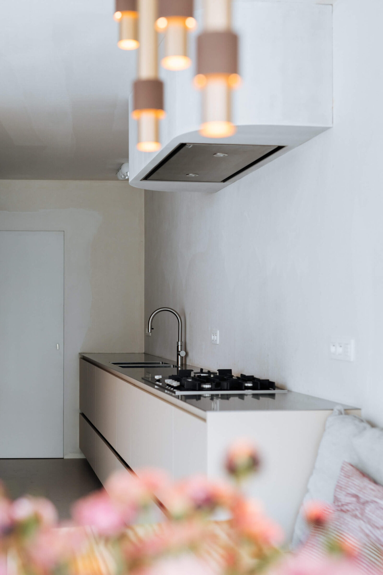Scandinavische keuken met lichte fronten, dampkap en koperen hanglampen in Lauwe, Kaster Keukens