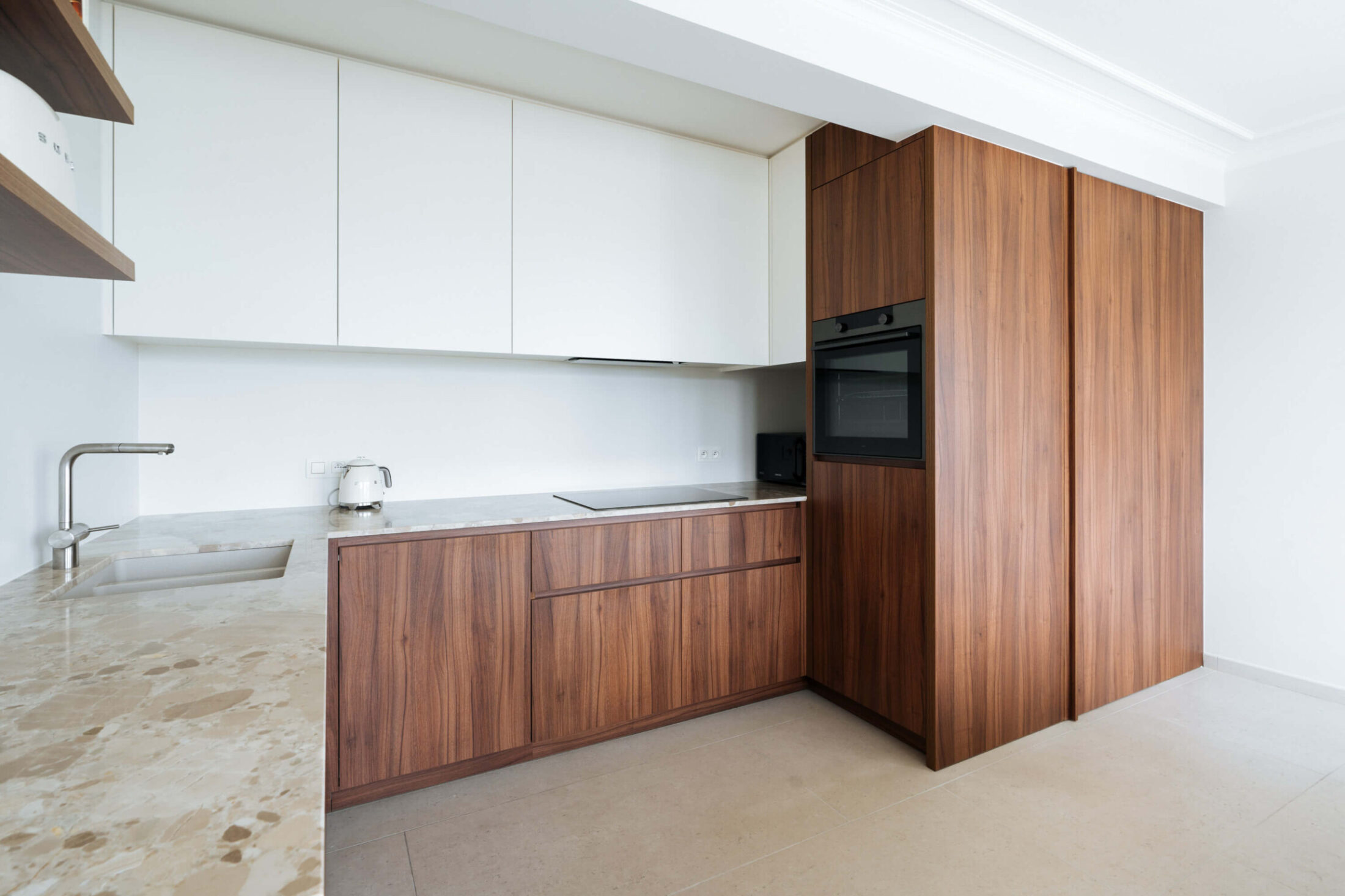 Scandinavische keuken met notelaren fronten, witte bovenkasten en gespikkeld werkblad in Oostende, Kaster Keukens