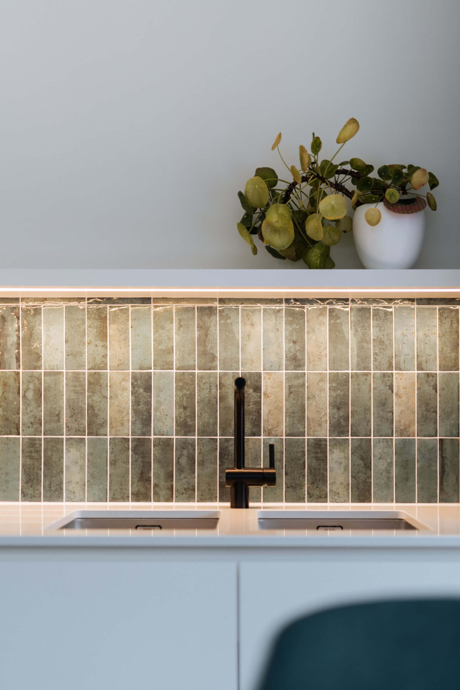 Detail van een Scandinavische keuken met groene wandtegels en zwarte kraan in Roeselare, Kaster Keukens