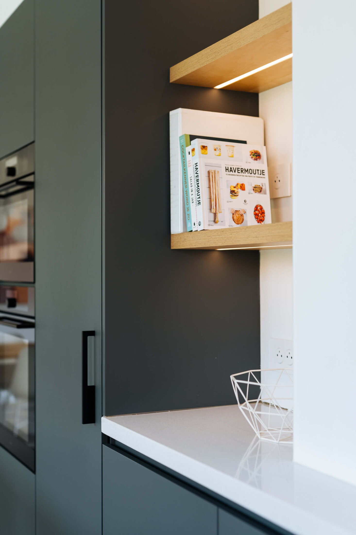 Detail van een Scandinavische keuken met donkerblauwe hoge kast en eiken nis in Roeselare, Kaster Keukens