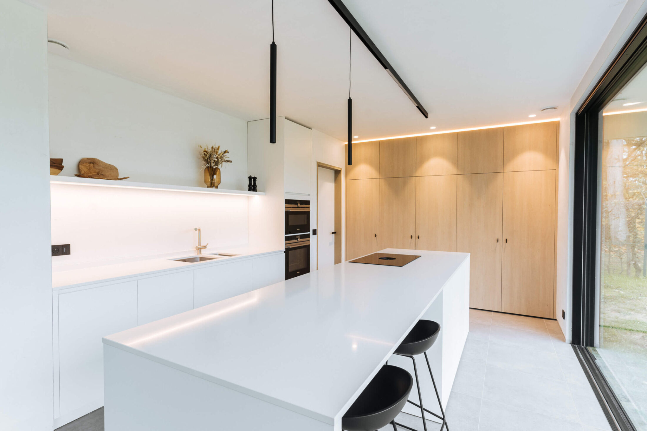 Scandinavische keuken met wit eiland, eiken kastenwand en zwarte hanglampen in Roeselare, Kaster Keukens