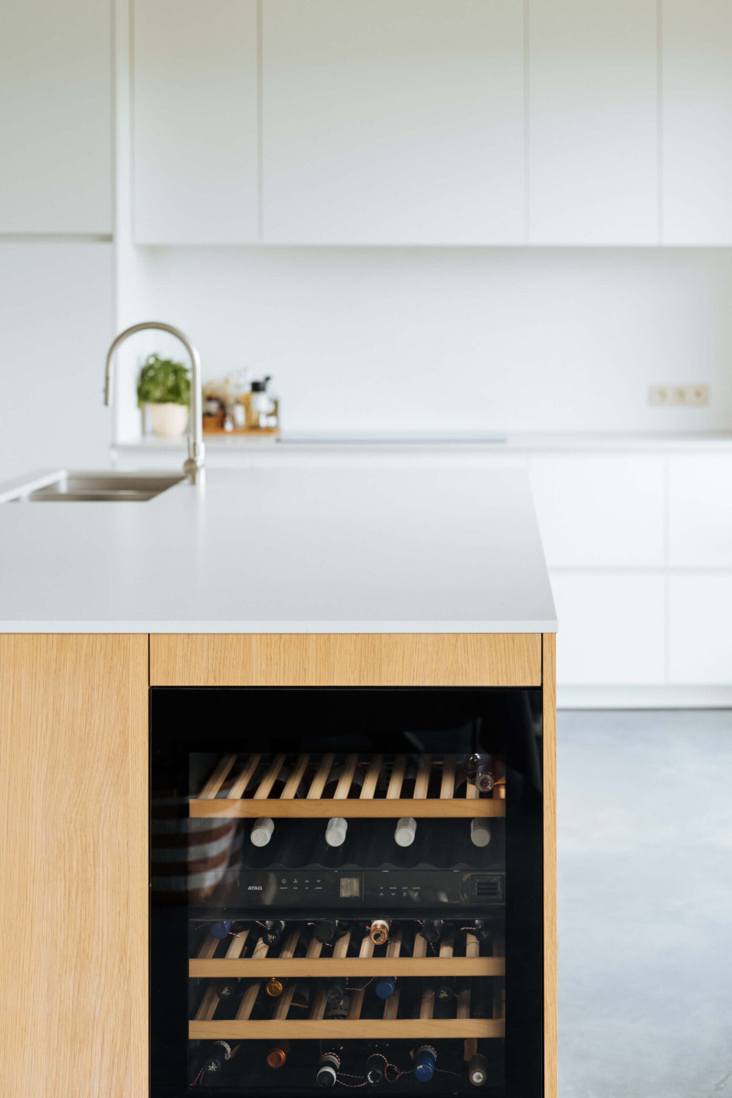 Scandinavische keuken met eiken eiland en ingebouwde wijnkoelkast in Wevelgem, Kaster Keukens
