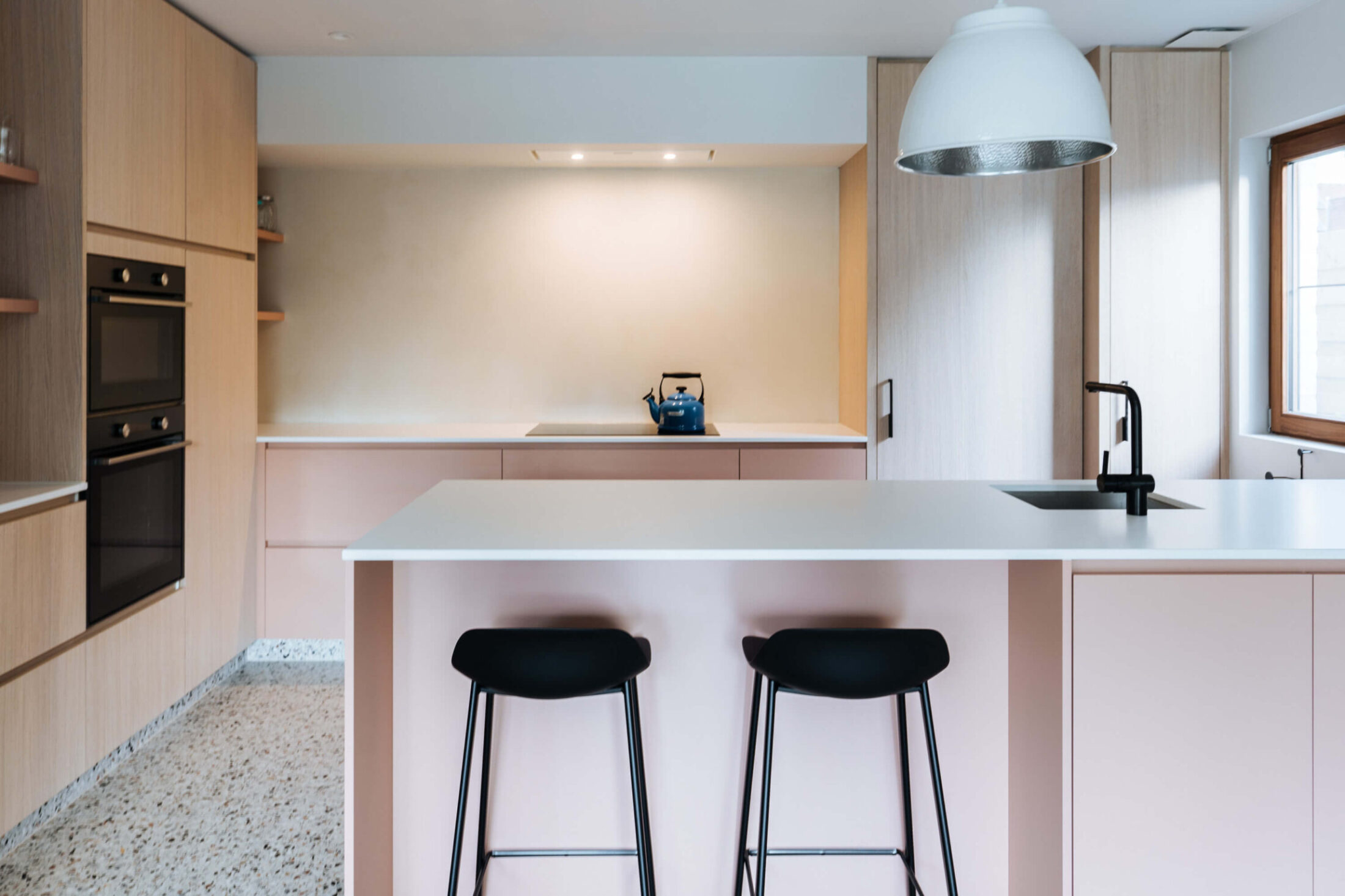 Scandinavische keuken met roze fronten, eiken kasten, eiland en terrazzovloer in Zedelgem, Kaster Keukens