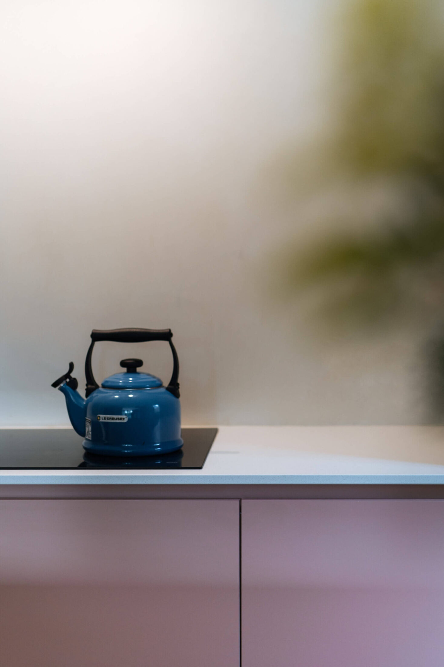 Detail van een Scandinavische keuken met roze fronten en blauwe ketel op de kookplaat in Zedelgem, Kaster Keukens