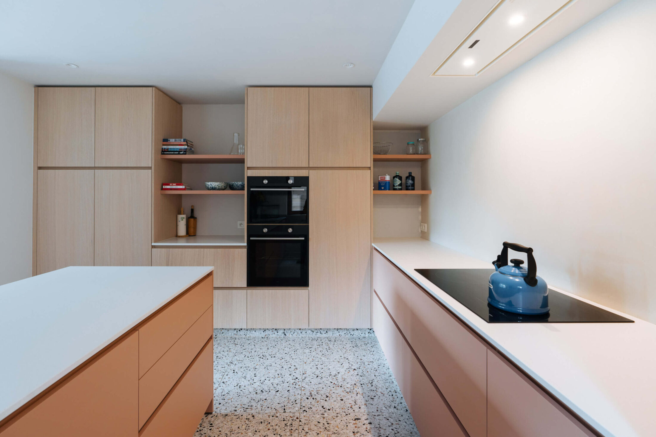 Scandinavische keuken met lichte houten kastenwand, twee ovens en inductiekookplaat in Zedelgem, Kaster Keukens