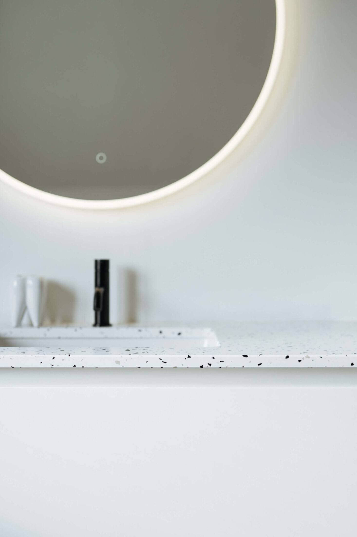 Detail van een badkamermeubel op maat met terrazzo blad en verlichte spiegel in Zedelgem, Kaster Keukens
