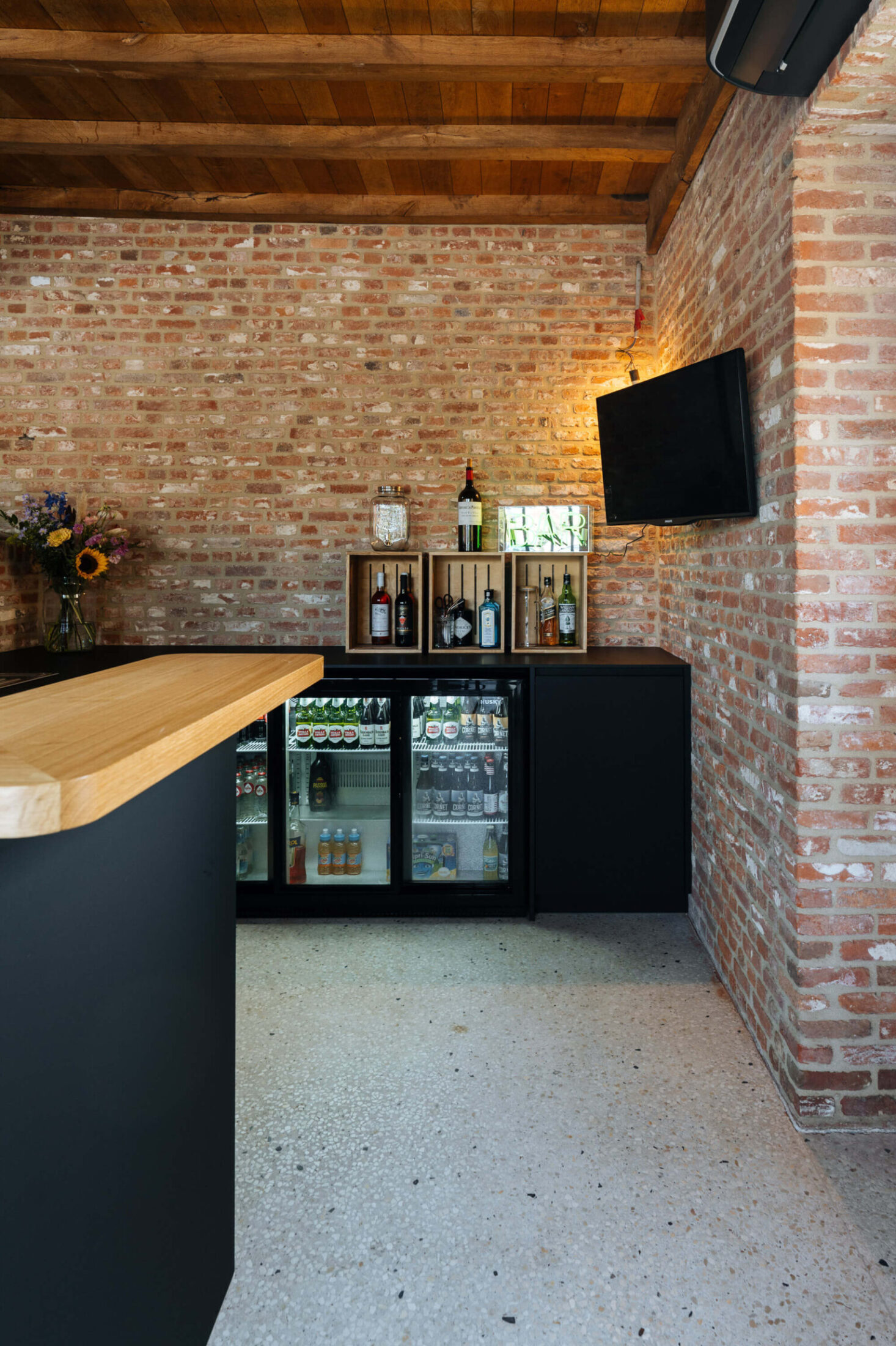 Bar op maat met houten toog en zwarte achterkast met drankkoelkasten in Beveren, Kaster Keukens