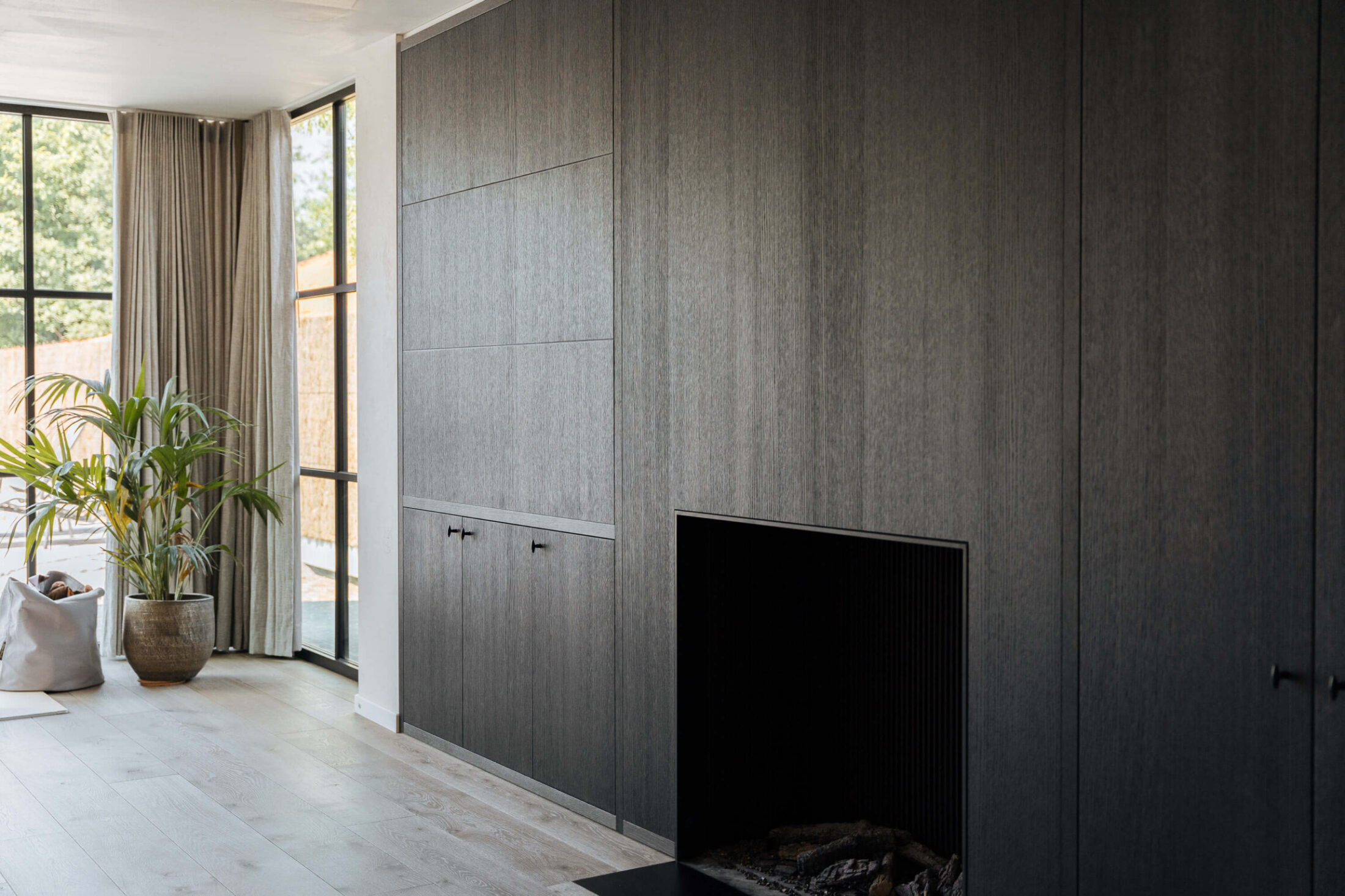 Kastenwand op maat in donker hout met ingebouwde haard in Lichtervelde, Kaster Keukens