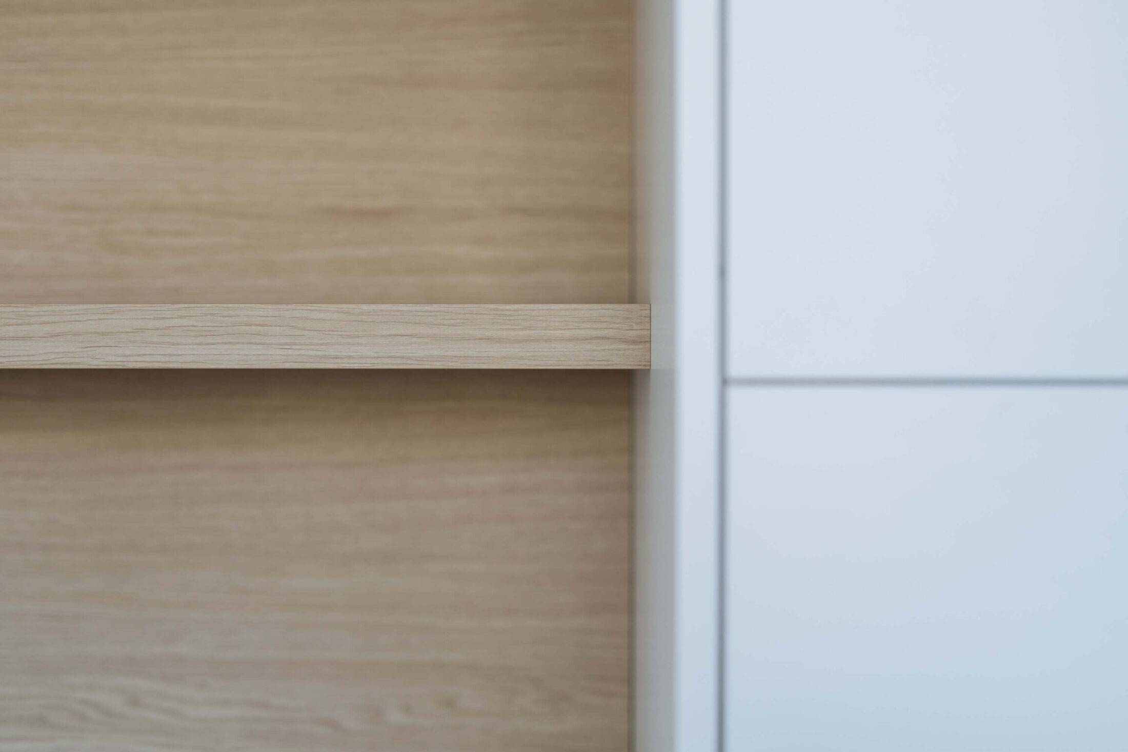 Detail van een eiken plank in een witte kastenwand op maat in Roeselare, Kaster Keukens