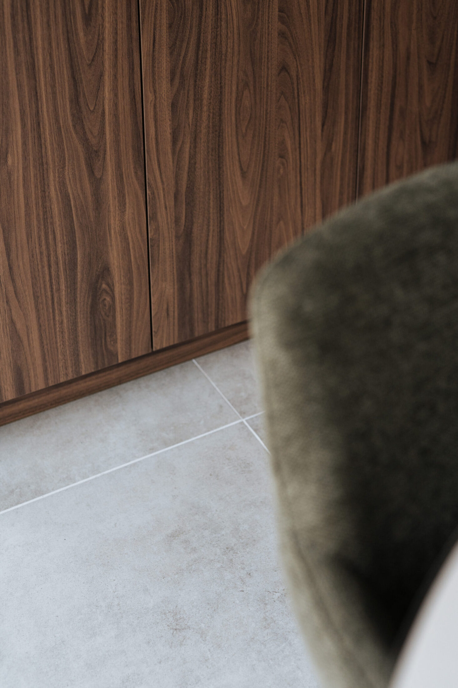 Detail van een moderne keuken met notelaar fronten en lichte betonlook vloer in Meulebeke, Kaster Keukens