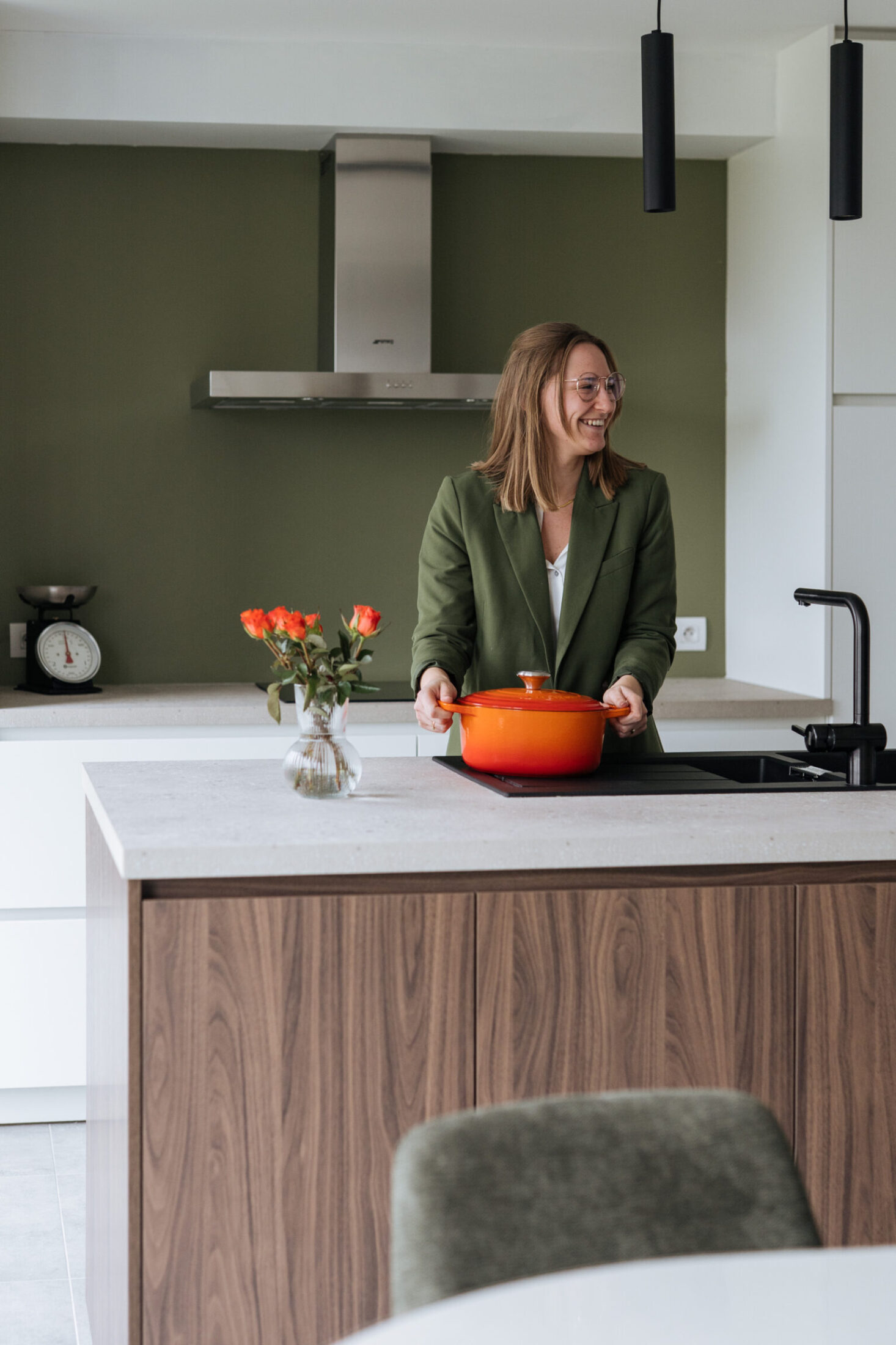 Moderne keuken met notelaar eiland, inox dampkap en groene wand in Meulebeke, Kaster Keukens