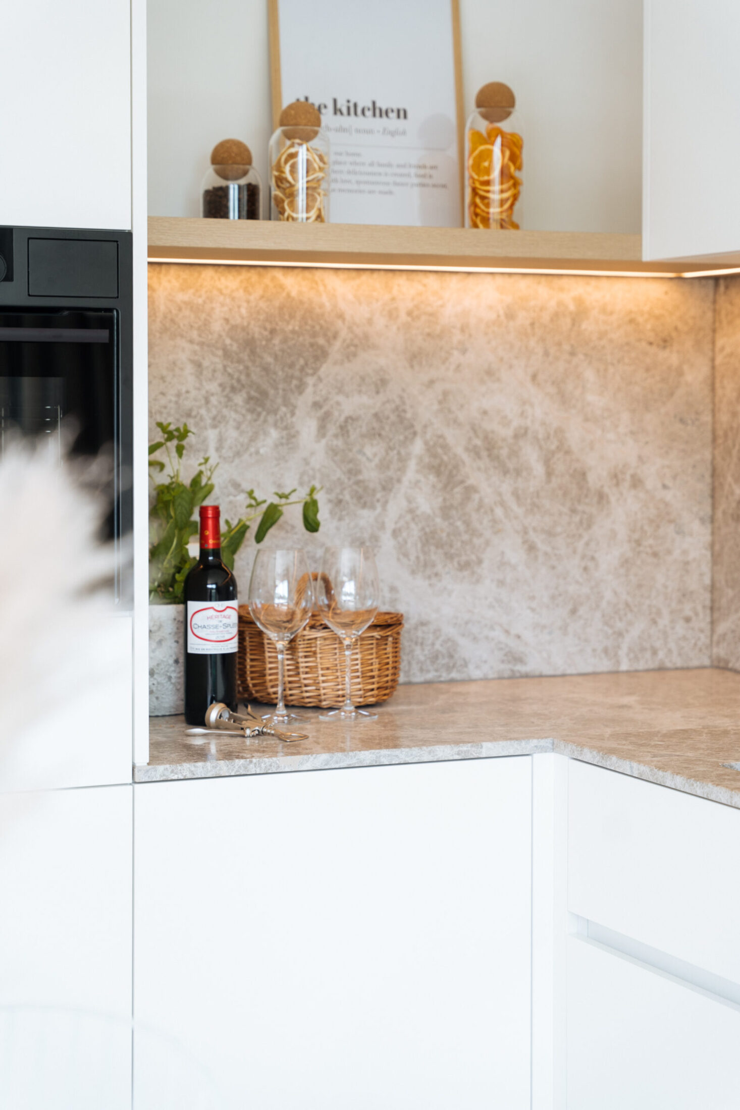 Detail van een moderne keuken met beige marmerlook werkblad en verlichte wandplank in Middelkerke, Kaster Keukens