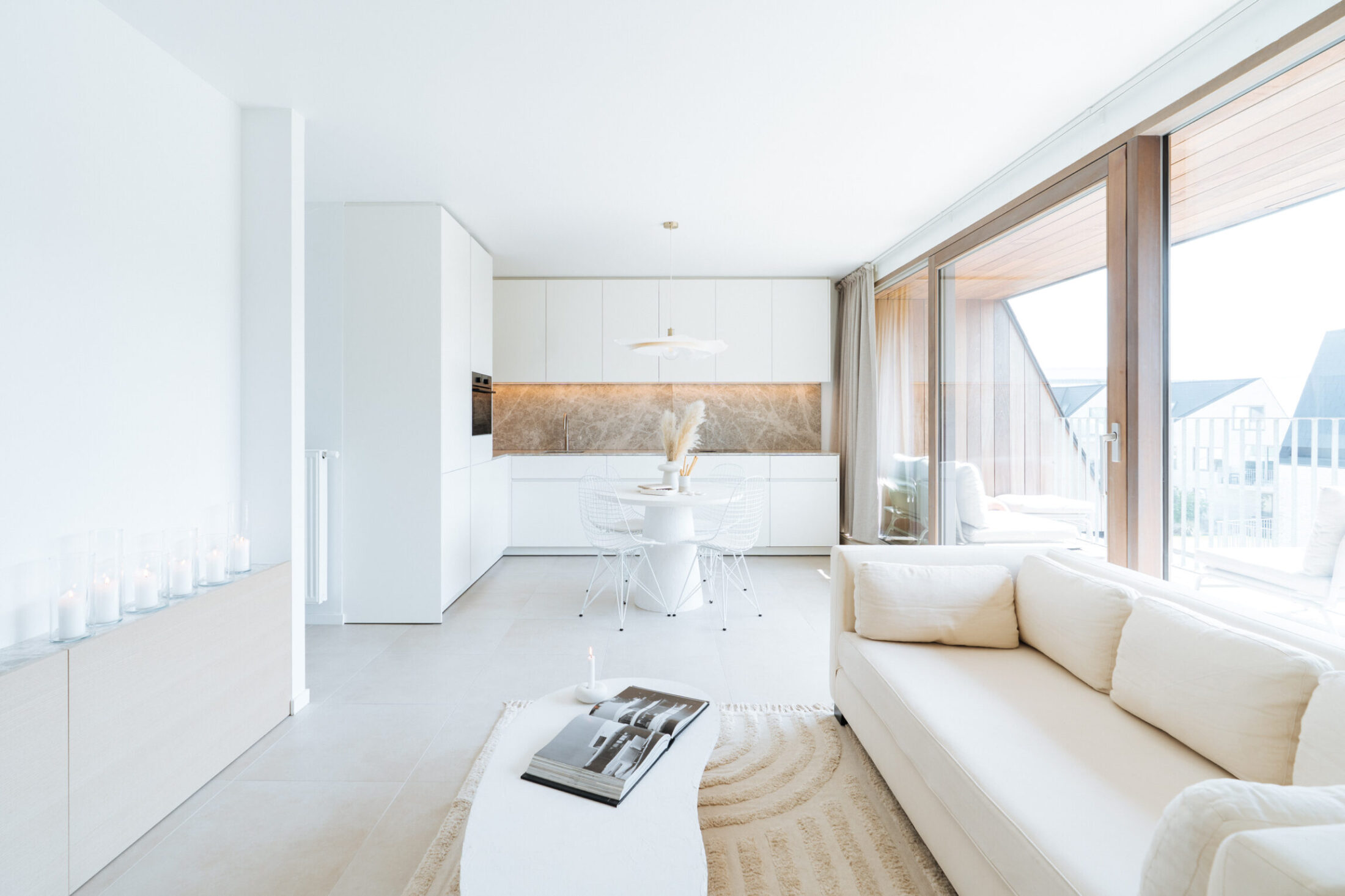 Moderne keuken met witte kasten in een open leefruimte met zithoek in Middelkerke, Kaster Keukens