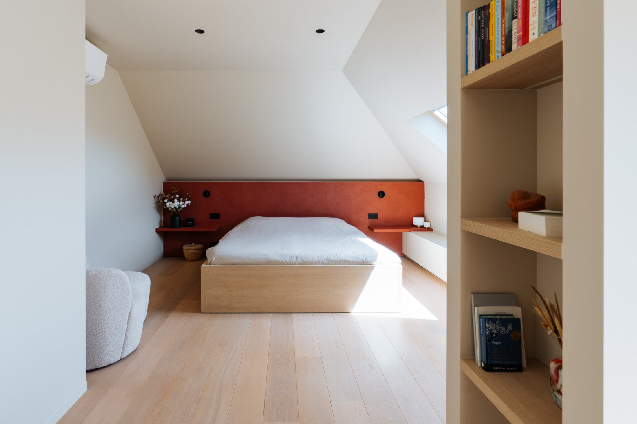 Bed met rood hoofdbord en open boekenkast op maat in een zolderkamer in Roeselare, Kaster Keukens
