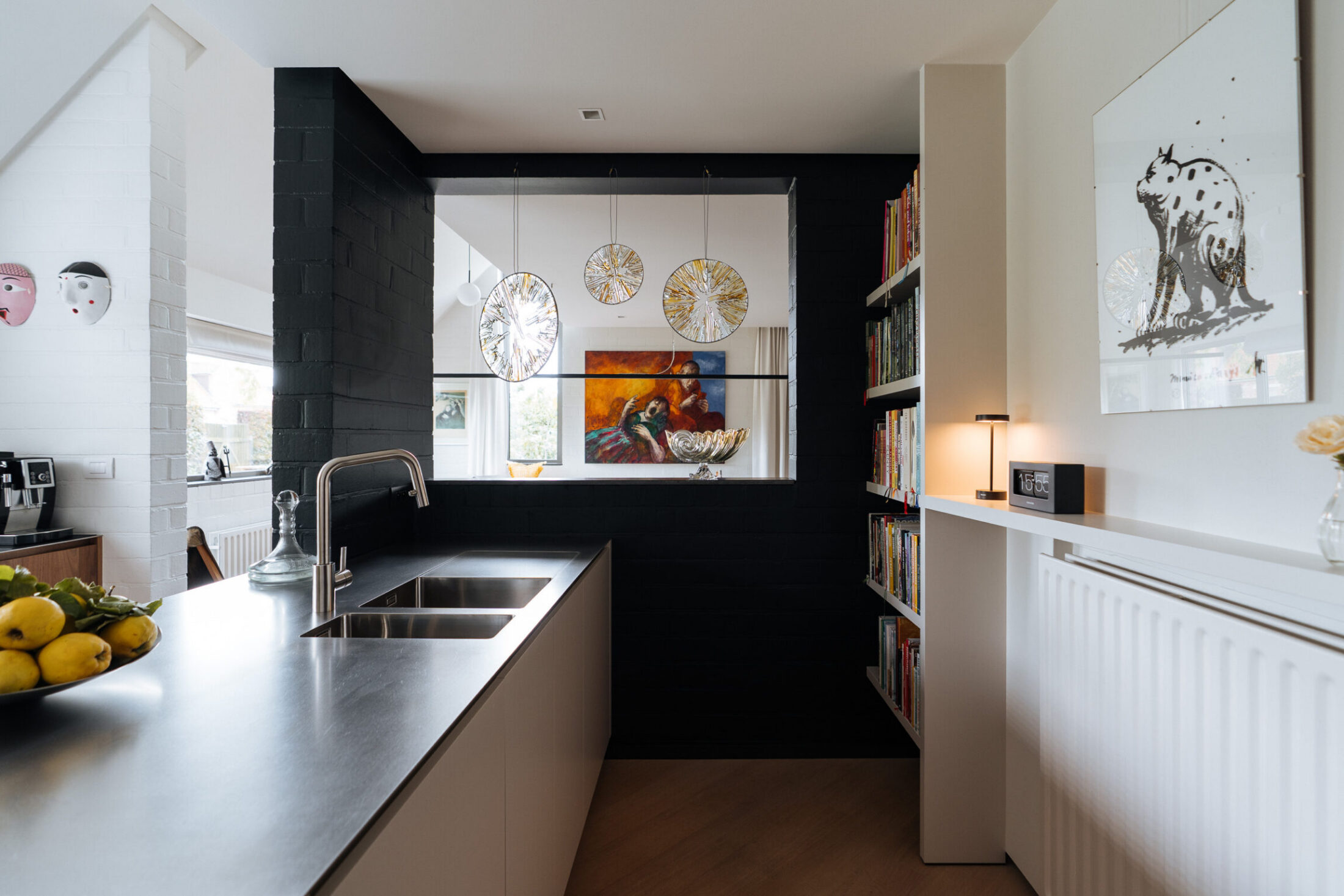 Moderne keuken met donker werkblad, inox spoelbak en zwarte wand met doorkijk in Izegem, Kaster Keukens