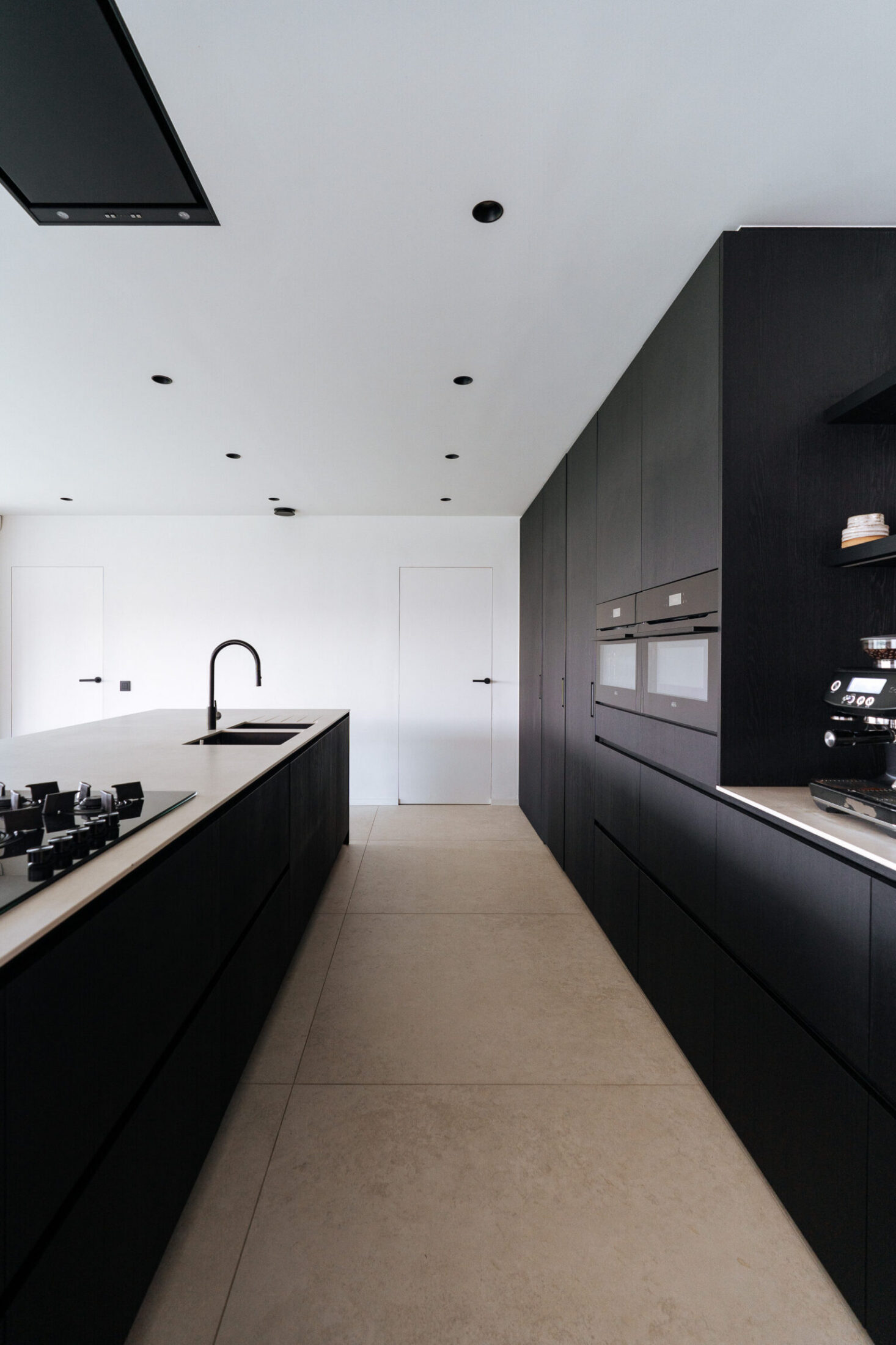 Moderne keuken met zwarte hoge kastenwand en eiland met licht werkblad in Moorsele, Kaster Keukens